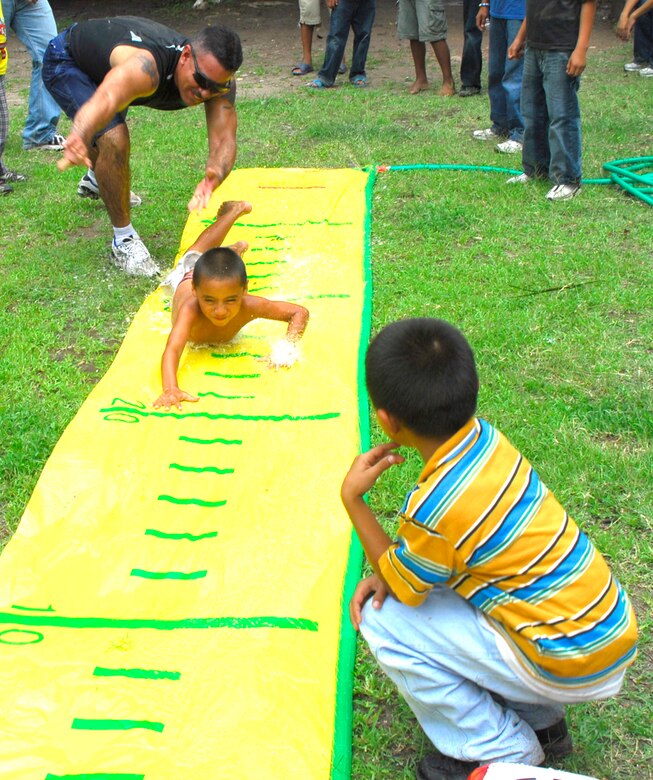 LA PAZ, Honduras ? Army Staff Sgt. Jeff Feliciano, Joint Task Force-Bravo 1-228th Aviation Regiment NCOIC Aviation Medicine, helps a child from the San Antonio Orphanage get a head start on a water game. More than 40 volunteers from JTF-Bravo, 1-228th Aviation Regiment and the Inter-American Air Force Academy NCO Course came to the orphanage to play games, have a cookout and spend time with children July 19.