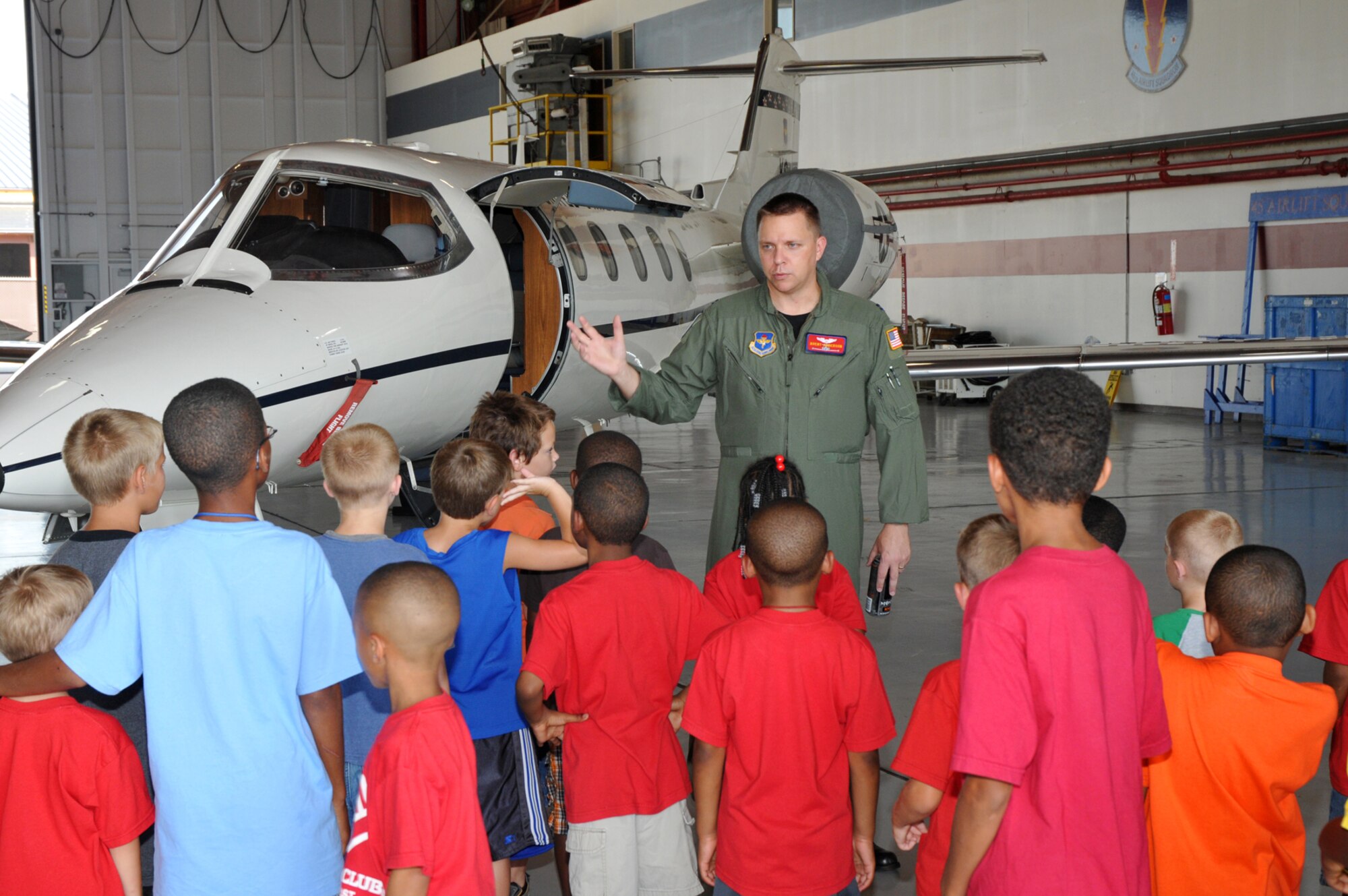 Capt. Brent Anderson, 45th Airlift Squadron, gives children from the Biloxi Boys and Girls Club a tour of a C-21 in Hangar 4 following a tour of the squadron’s headquarters in Lott Hall, July 16.  (U.S. Air Force photo by Adam Bond)