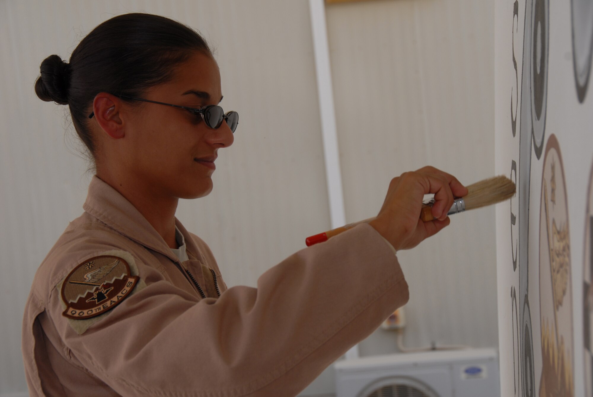 Senior Airman Nicole Singh, an Air Surveillance Technician with the 960th Expeditionary Airborne Air Control Squadron, puts the finishing touches on her mural for the 960th EAACS. (Photo by Tech. Sgt. Christopher A. Campbell)  