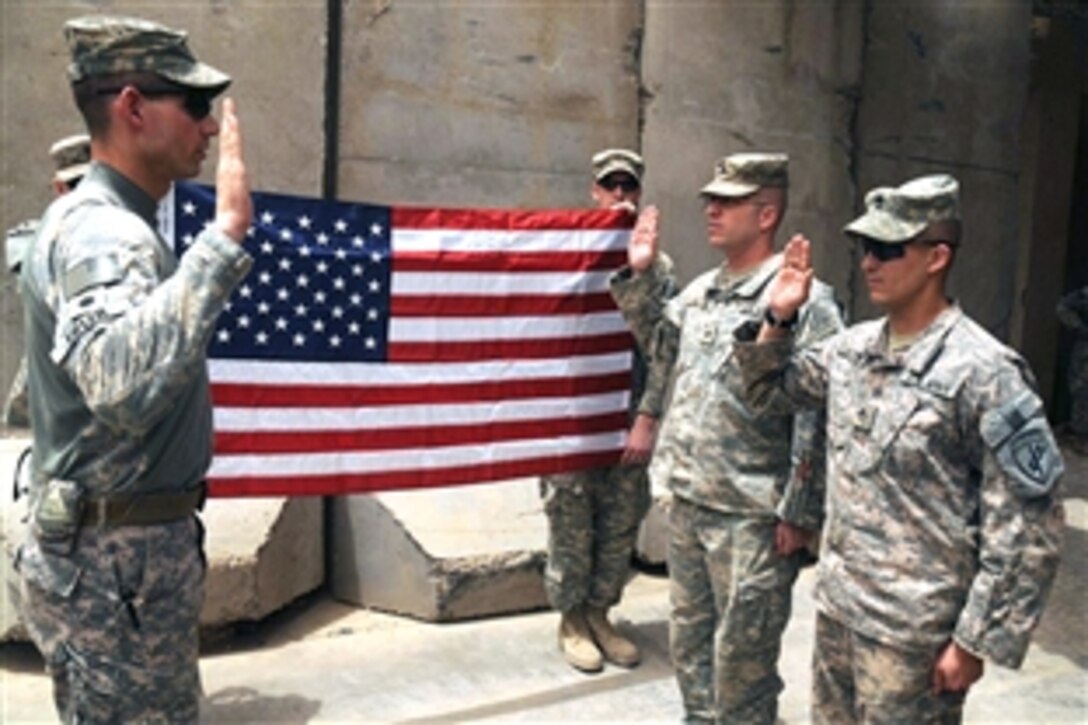 U.S. Army Lt. Col. Brian Eifler, commander of Task Force Regular 1st Battalion, 6th Infantry Regiment, performs the reenlistments of Sgt. Vincent Ruiz and Staff Sgt. Frank Lugo at Joint Security Station in the Sadr City district of Baghdad, Iraq, July 16, 2008. Lugo and Ruiz are assigned to the 404th Civil Affairs unit. 
