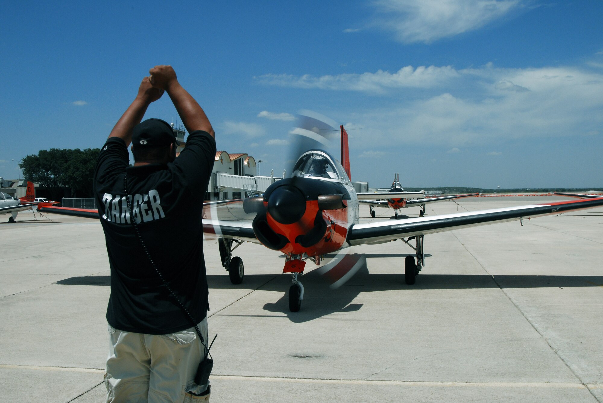 An employee of Ranger Aviation brings a Navy T-34 trainer aircraft to a full stop July 22 at Mathis Field Airport in San Angelo, Texas. Twenty-three aircraft were sent from Corpus Christi Naval Air Station to Mathis Field, their designated inland airport, to escape potential damage from Hurricane Dolly. (U.S. Air Force photo/Paul R. Martin)