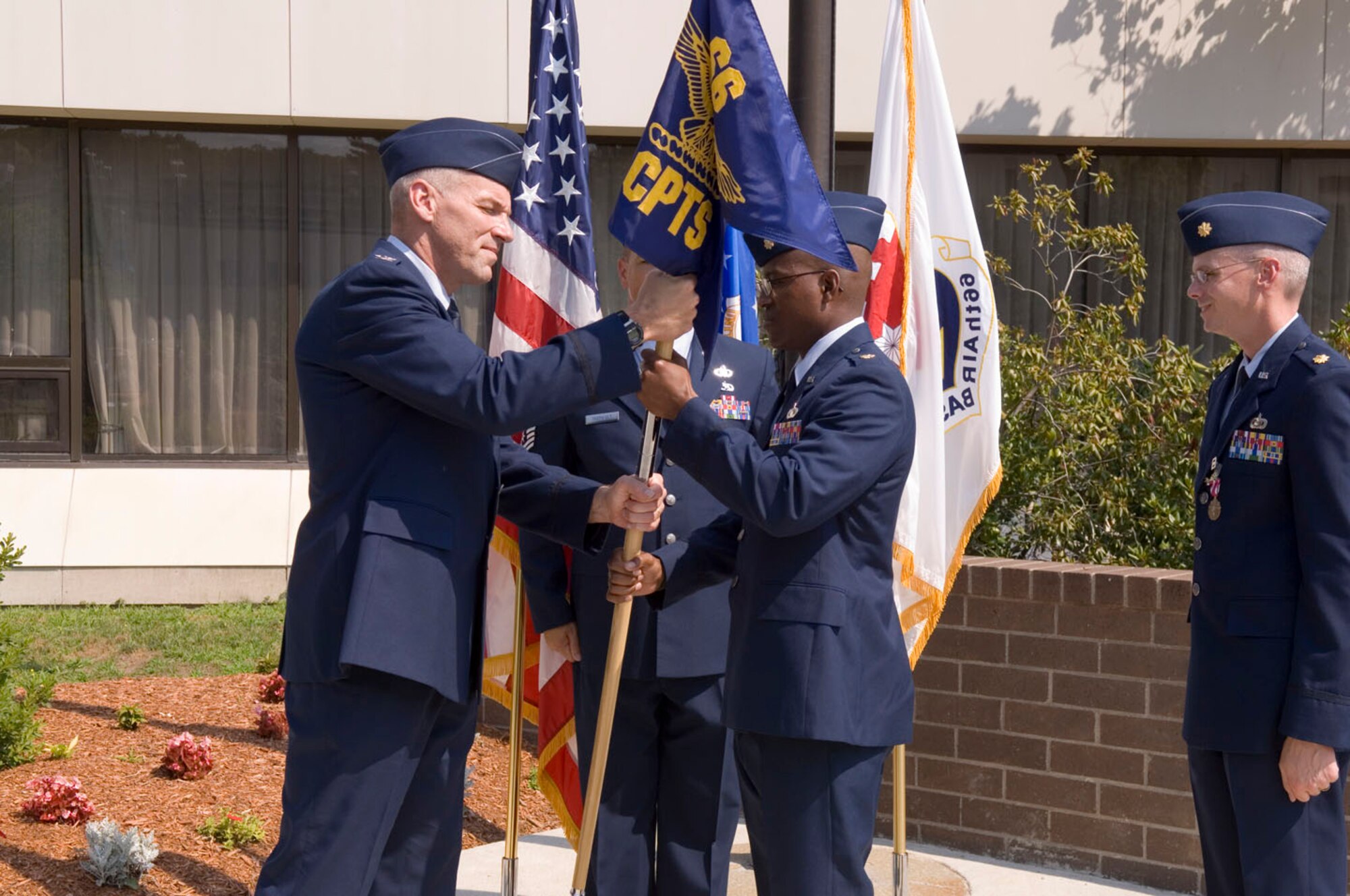HANSCOM AFB, Mass. -- Col. Tom Schluckebier (left), 66th Air Base Wing commander, passes the 66th Comptroller Squadron flag to Maj. Ned June during the squadron's change of command ceremony July 18 in front of the Brown Building. Major June replaced Maj. Robert White who recently returned from an overseas deployment. (U.S. Air Force photo by Rick Berry)