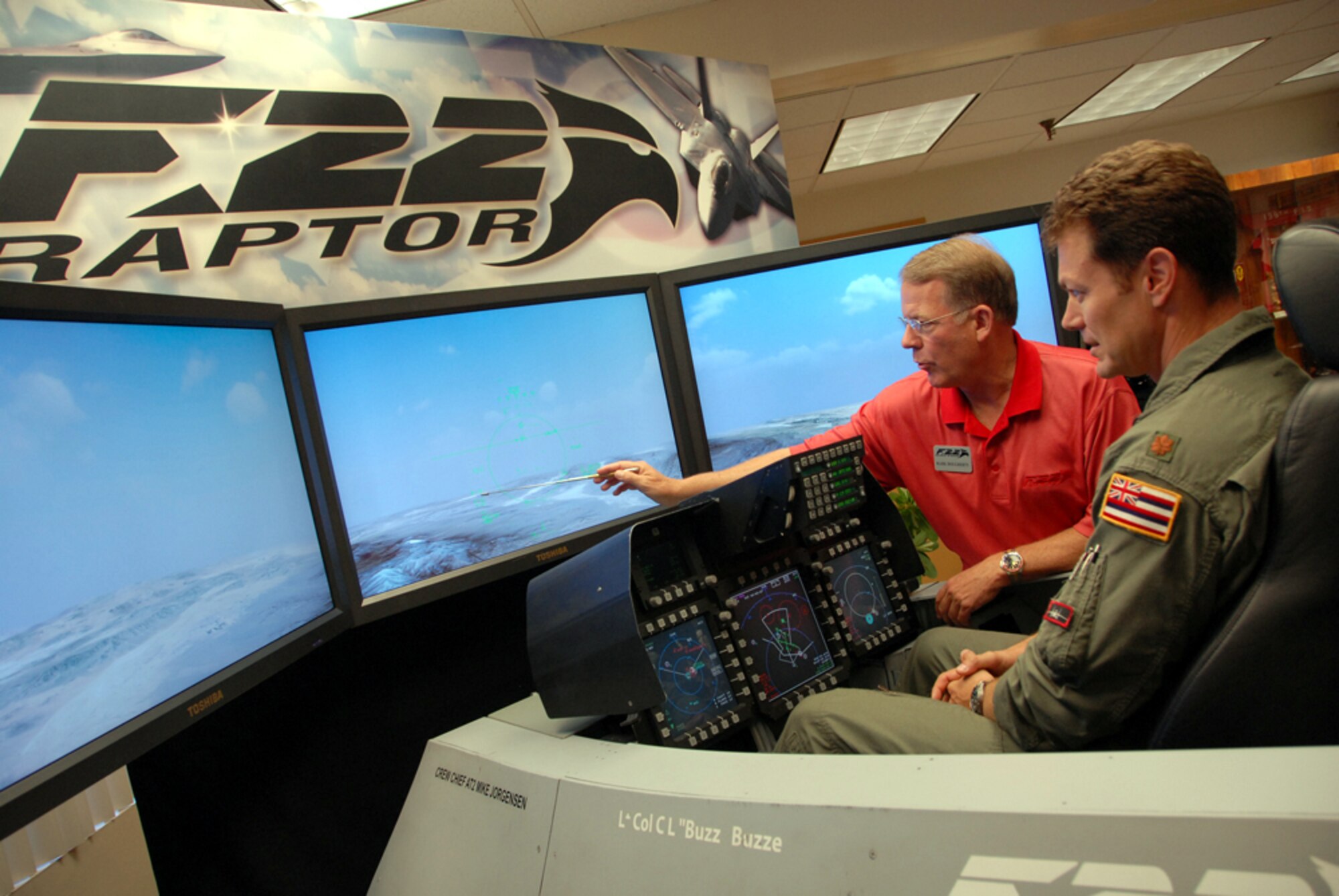 HICKAM AIR FORCE BASE, Hawaii -- Mark Dougherty, from Lockheed Martin Aeronautics Company demonstrates the F-22 Raptor flight simulator to Major James "Saw" Sage, a F-15 pilot with the 199 th Figher Squadron, Hawaii Air National Guard here July 22. The F-22 Raptor is the Air Force's newest fighter aircraft. Its combination of stealth, supercruise, maneuverability, and integrated avionics, coupled with improved supportability, represents an exponential leap in warfighting capabilities. (U.S. Air Force photo/ Master Sgt. Kristen Stanley)
