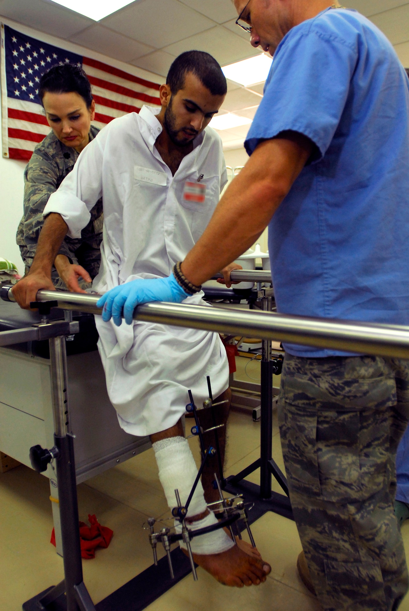JOINT BASE BALAD, Iraq -- Lt. Col. Lisa Smith and Tech. Sgt. Daniel Wilson help Iraqi local Moqdad, whose leg was shattered two months ago, take his first steps in two weeks during a physical therapy appointment at the Air Force Theater Hospital here July 22. Moqdad is an Iraqi local whose leg was shattered two months ago. The hospital's Occupational Therapy and Physical Therapy Clinic provides care for Iraqi patients twice a week. Colonel Smith, element chief of occupational and physical therapy for the 332nd Expeditionary Medical Operations Squadron, is deployed from Lackland Air Force Base, Texas. Sergeant Wilson, a physical medicine technician with the 332nd EMDOS, is deployed from Hill AFB, Utah. (U.S. Air Force photo/Airman 1st Class Jason Epley)
