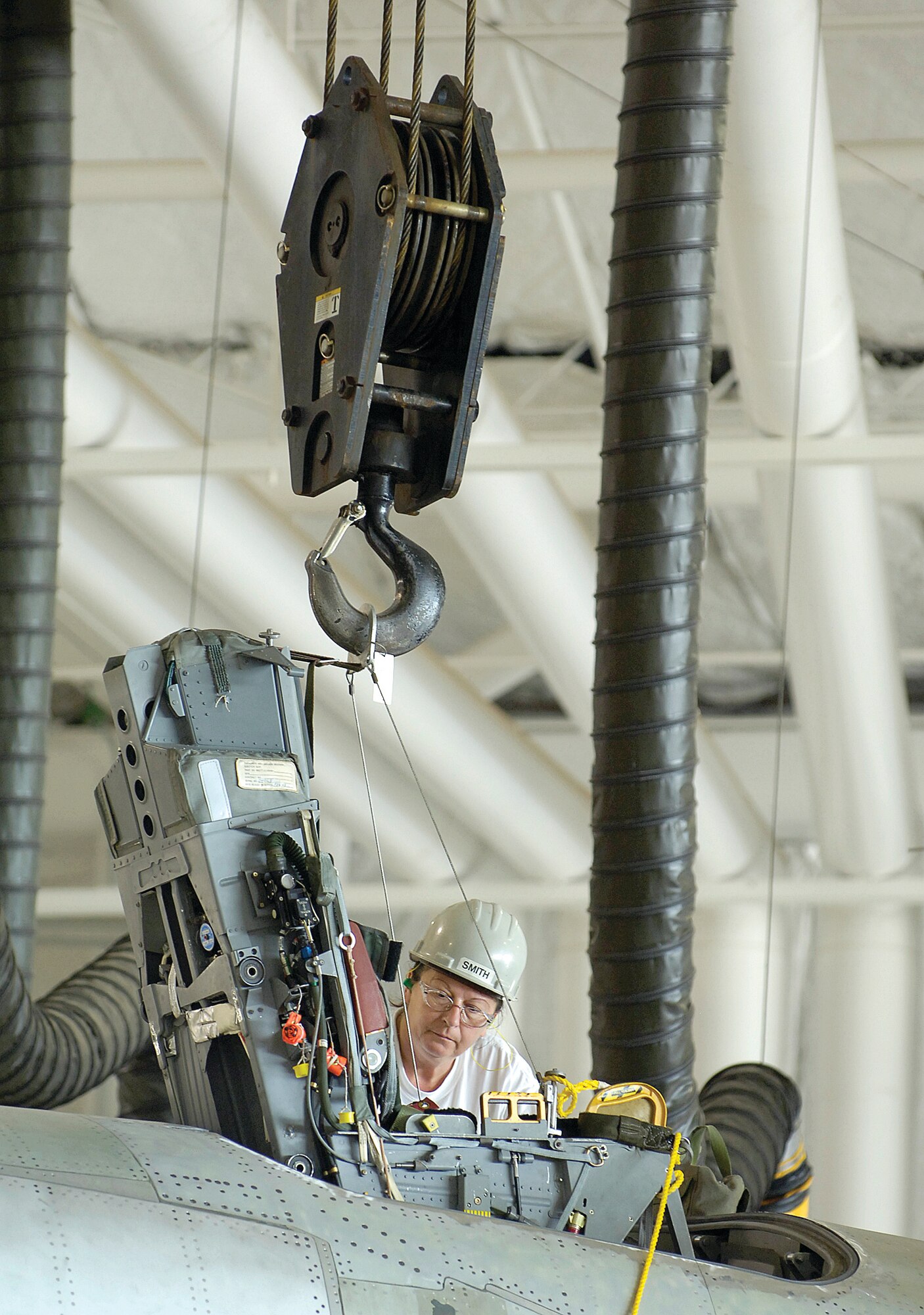 JoRita Moss guides the pilot’s ejection seat from the B-1 cockpit as a crane lifts and moves it to a waiting crew on the ground.  The egress mechanics of the 565th Aircraft Maintenance Squadron will replace the seats and rails that would eject the four-person crew away from the aircraft within seconds during an emergency.  The work is part of the planned maintenance.(Air Force photo/Margo Wright)
