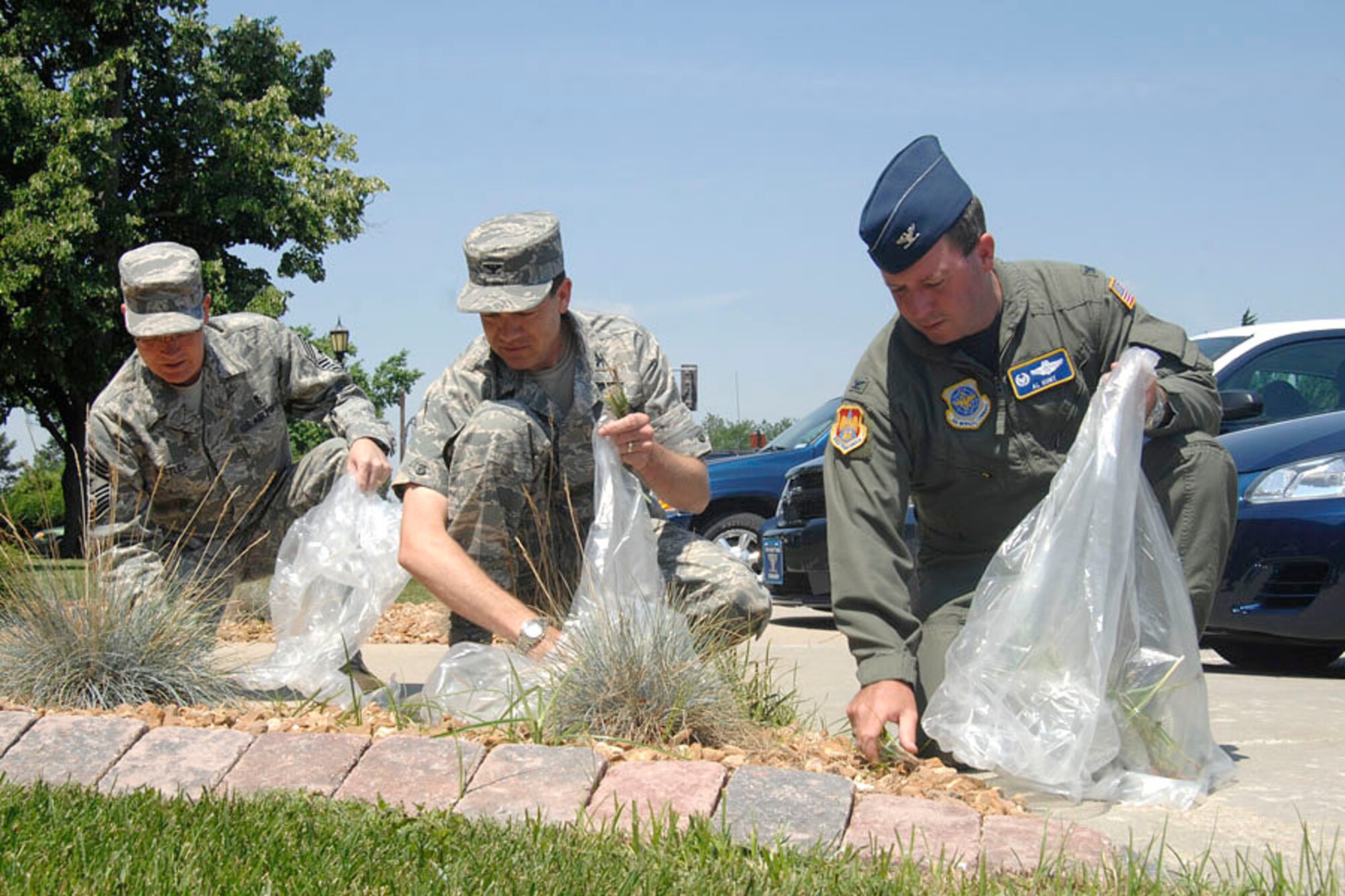 SCOTT AIR FORCE BASE, Ill. -- Col. Al Hunt (right), 375th Airlift Wing commander, Col. Stephen Oliver (center), 375th Airlift Wing vice commander and Chief Master Sgt. James Suttles, 375th Airlift Wing command chief, help keep Scott looking its best by pulling weeds behind the 375th Airlift Wing headquarters building. Colonel Hunt, Colonel Oliver and Chief Suttles hope to set an example that everyone can do their part to help make Scott a better place. 
(US Air force photo/Senior Airman Jonathan Lovelady)