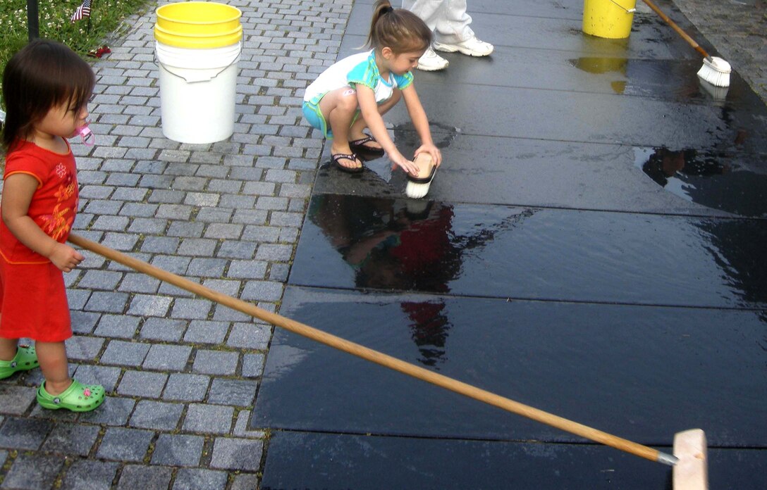 WASHINGTON, D.C. -- Two-year-old Chloe Spangler and 4-year-old Lauren Eckert scrub a pathway that follows the nearly 247-foot Vietnam Memorial Wall here July 20. The volunteer wall washing is a way for service members to thank fallen service members and was conducted under the guidance of the National Park Service. The NPS coordinates volunteers to clean the wall each week, or 52 times per year. At dawn, more than 20 members of the 459th Air Refueling Wing, family and other volunteers stood face to face with their own reflections while washing more than 58,000 names of service members on the wall. Chloe is the daughter of Master Sgt. Camila Eckert (not shown), 459th Mission Support Flight wing career assistance advisor, and Lauren is the daughter of Master Sgt. Sally Spangler (not shown), 459th MSF family support manager. (U.S. Air Force photo/Tech. Sgt. Amaani Lyle)