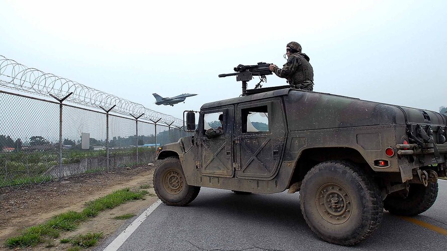 OSAN AIR BASE, Republic of Korea – Airman 1st Class Michael Wittman, 51st Security Forces Squadron guards the base perimeter as an F-16 makes its' landing approach during exercise Beverly Bulldog 08-03. The 51st SFS Defenders play a key role in securing the base during training and real world situations. (U.S. Air Force photo/Master Sgt. Marlin Zimmerman)