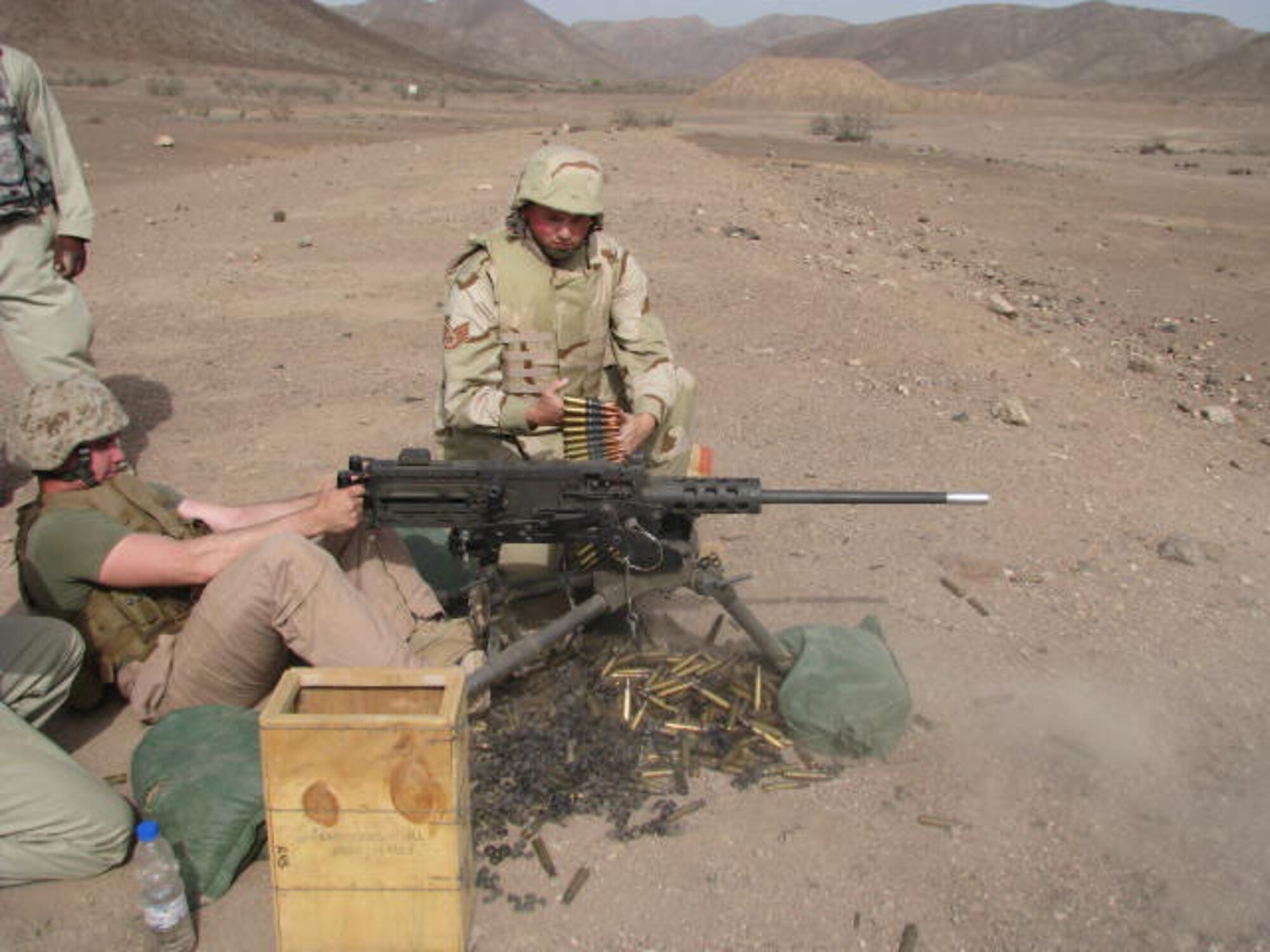 SEYMOUR JOHNSON AIR FORCE BASE, N.C. -- Staff Sergeant Aaron Walker (center) assists Corporal Brent Farnen, U.S. Marine Corps, with firing the .50 calibur machine gun at a firing range just outside of Djibouti City, Djibouti during a training exercise.  Sergeant Walker is deployed as a member of the Combined Joint Task Force, Horn of Africa, and is assigned to the 916th Communications Squadron, Air Force Reserve.