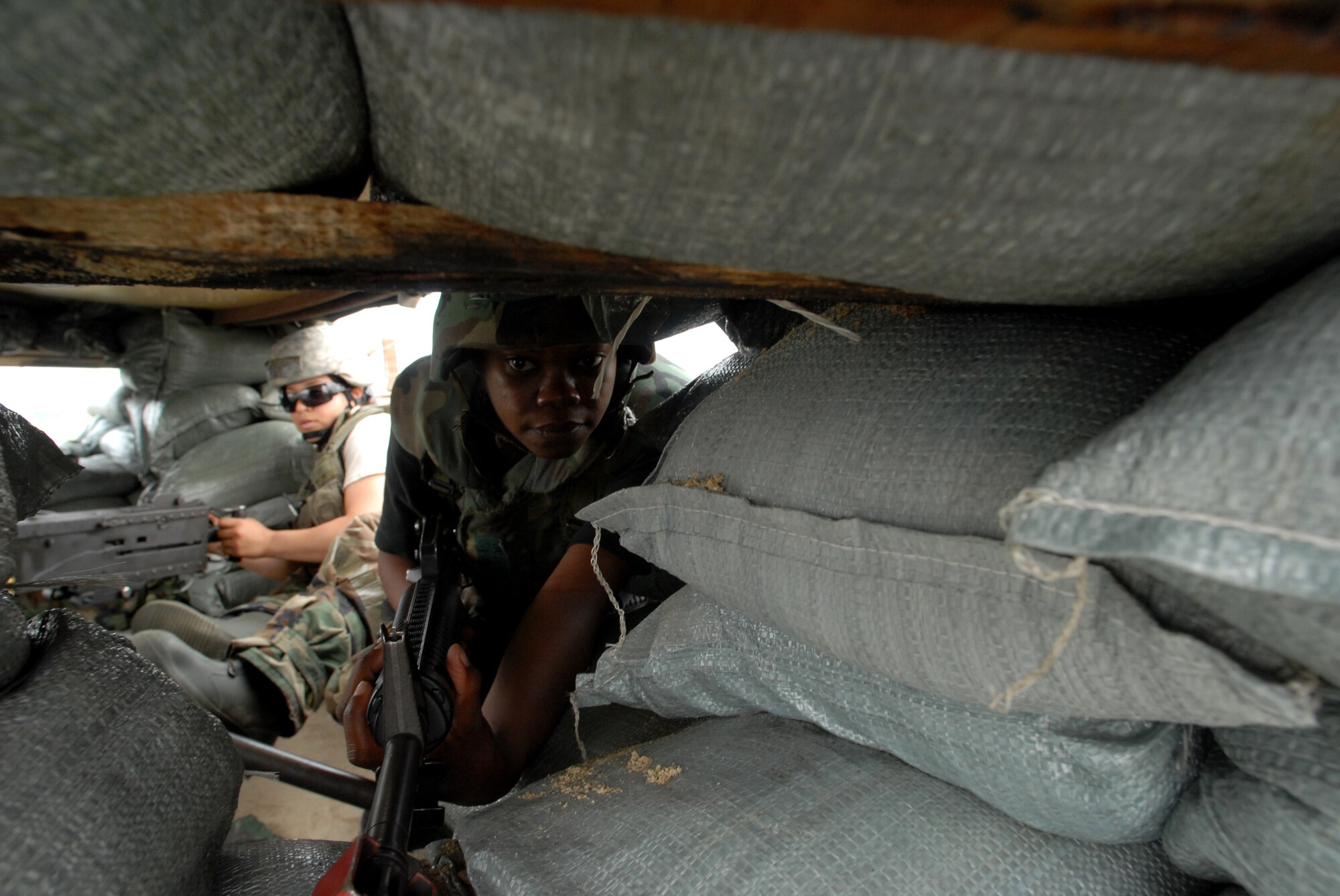 Senior Airman Keyandra Holland, a security forces augmentee, takes cover in a defensive fighting position and monitors the perimiter, while Airman 1st Class Loriane Cabera, 8th Security Forces Squadron, defends the bunker with a .50 Caliber Machine Gun during the BEVERLY BULLDOG 08-03 peninsula wide operational readiness exercise here July 23. The PENORE is a training exercise among United States Forces in Korea, keeping Wolf Pack Airmen ready to execute the mission. (U.S. Air Force photo by: Senior Airman Angela Ruiz)