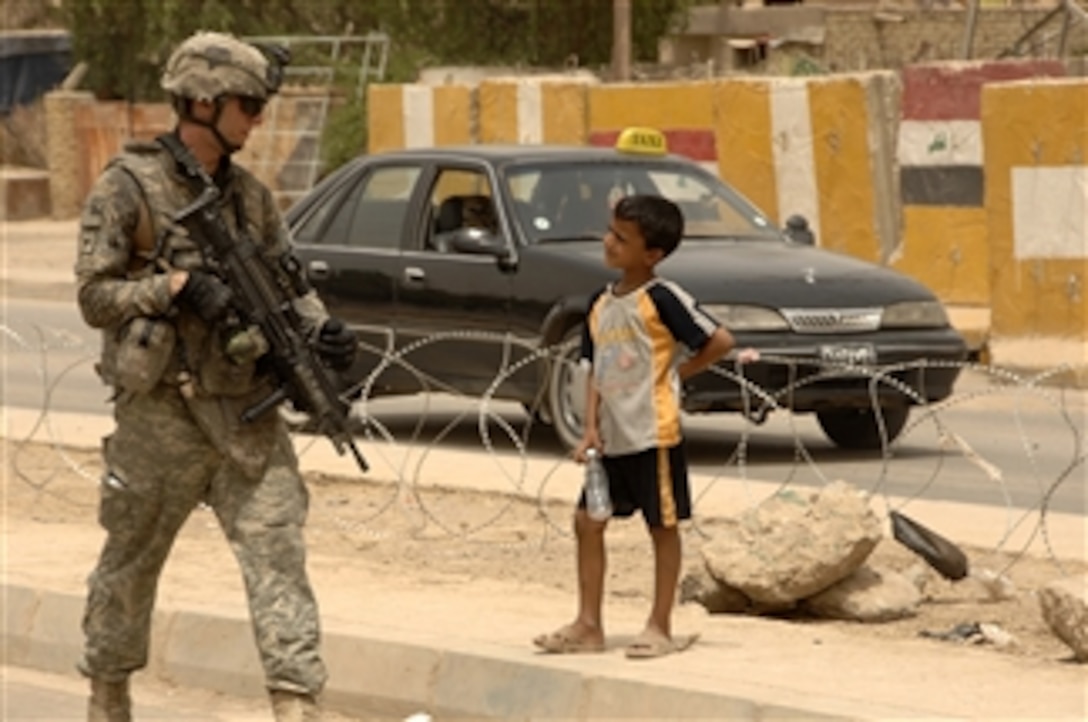 An Iraqi boy watches as U.S. Army Spc. Justin Officer passes by during a combined dismounted patrol with Iraq police in the Ghazaliya district of Baghdad, Iraq, on July, 17, 2008.  The soldiers are assigned to the 2nd Platoon, Bravo Troop, 1st Squadron, 75th Cavalry Regiment, 2nd Brigade Combat Team, 101st Airborne Division.  