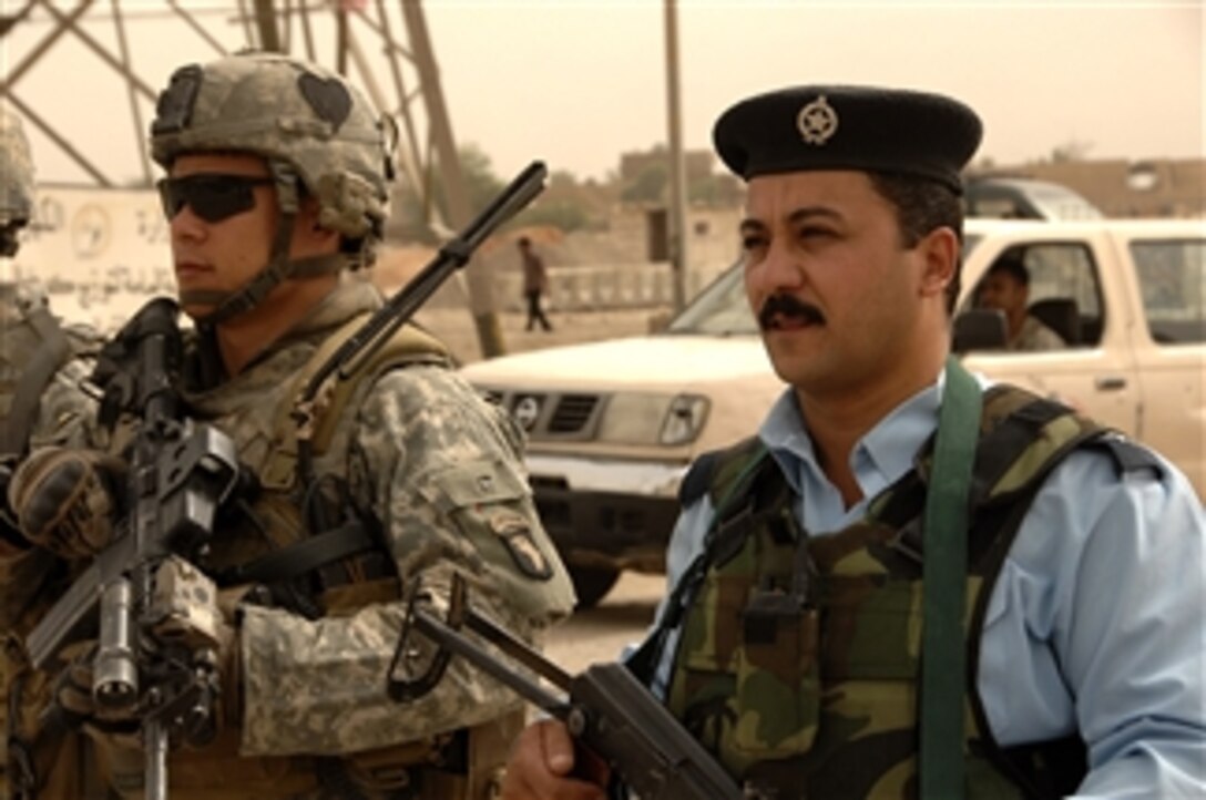 U.S. Army 1st Lt. Ryan Chang (left) and Iraqi police Lt. Akil walk out of Joint Security Station Ghaz 4 during a combined dismounted patrol in the Ghazaliya district of Baghdad, Iraq, on July, 17, 2008.  The soldiers are assigned to the 2nd Platoon, Bravo Troop, 1st Squadron, 75th Cavalry Regiment, 2nd Brigade Combat Team, 101st Airborne Division.  