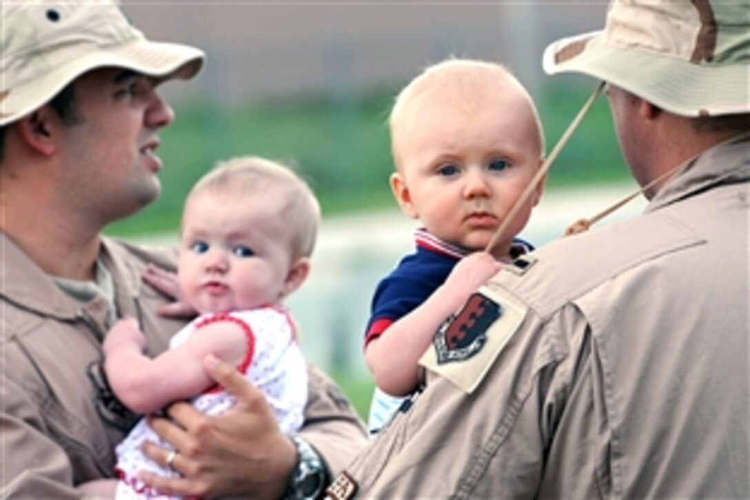 U.S. Air Force Capt. Steven Fowler, left, a weapons system operator, and 1st Lt. Daniel Silk, a B-1 Bomber pilot, hold their children prior to departing Ellsworth Air Force Base, S.D., July 22, 2008. Fowler and Silk are assigned to the 34th Bomb Squadron. More than 200 airmen are deploying to support Operation Iraqi Freedom and Operation Enduring Freedom. 