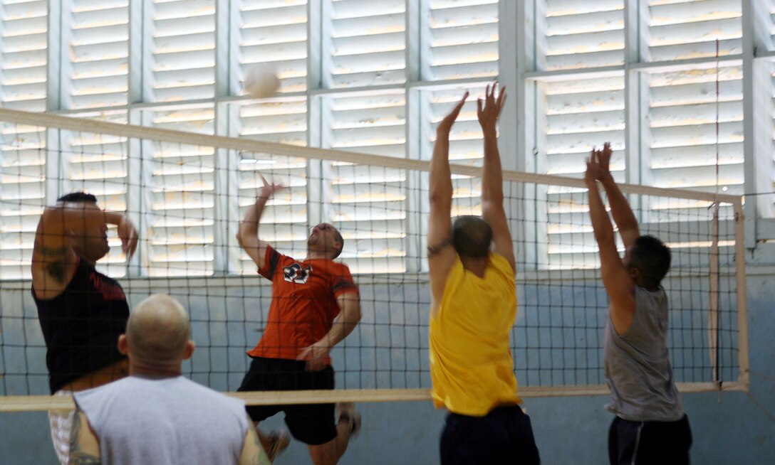 Ryan Wassink, Aches and Pains 2's left forward, jumps to spike a high ball through CMSAPAC defenders Aaron Kennedy (center) and Ben Duong during a 2008 Intramural Volleyball League game at the gymnasium July 24 here.