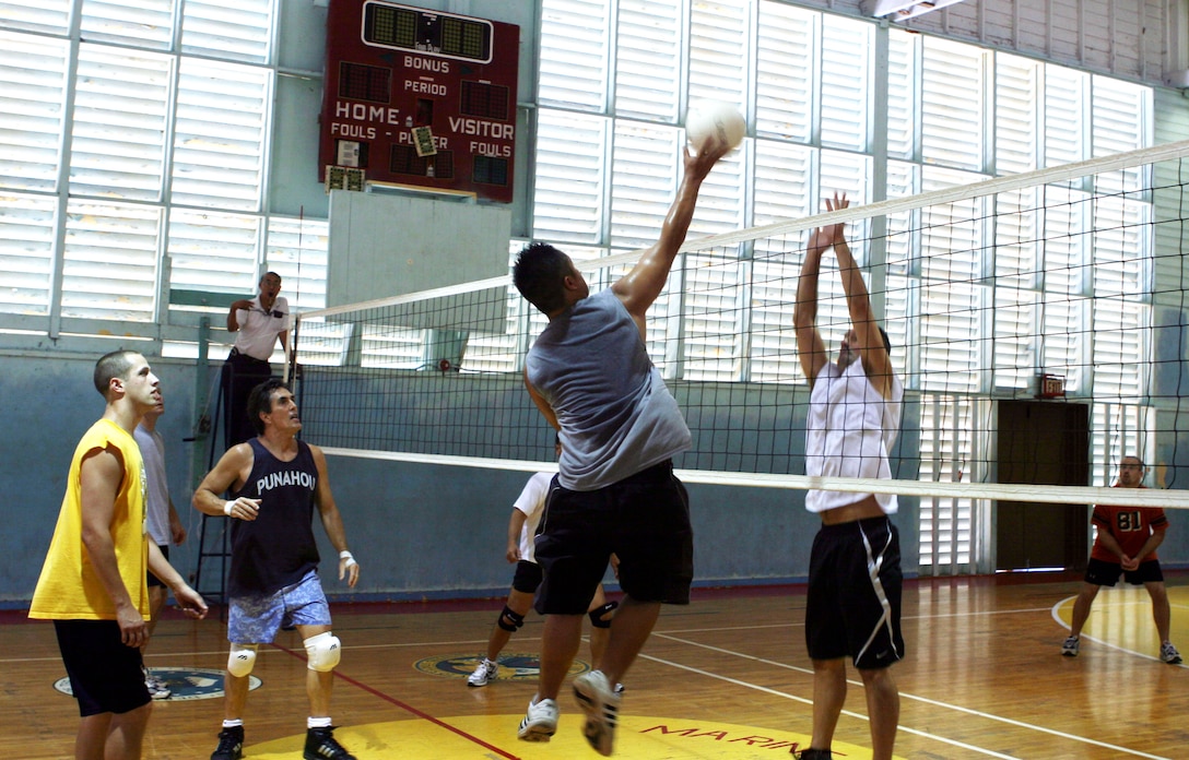 Ben Duong, CMSAPAC's right forward, pushes the ball up and over the hands of Robert O'Toole, Aches and Pains 2's center forward, during a 2008 Intramural Volleyball League game at the gymnasium July 24 here.