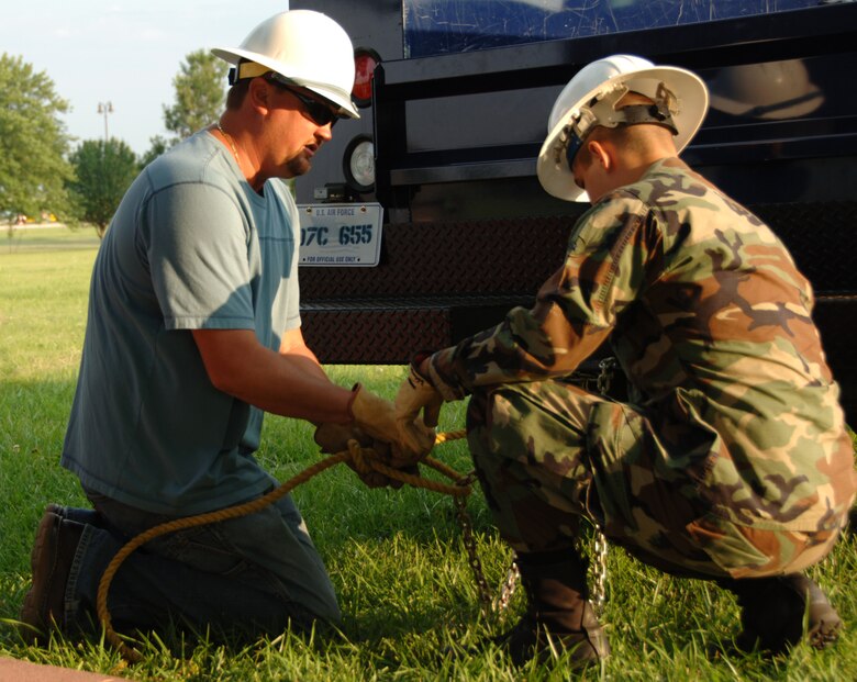 Shannon Gilcrest instructs Airman Basic Brad Vanzandt, a Reservist assigned to the 931st Air Refueling Group at McConnell Air Force Base, Kan., how to attach a chain to a rope that will be used to pull underground wires.  An Air Force Reserve program is providing funds for Airman Vanzandt to train with Mr. Gilcrest's active-duty civil engineer squadron at McConnell. The program is designed to speed up the training of traditional Reservists beyond what one weekend a month and a few weeks a year usually allows. (U.S. Air Force photo/Tech. Sgt. Jason Schaap)