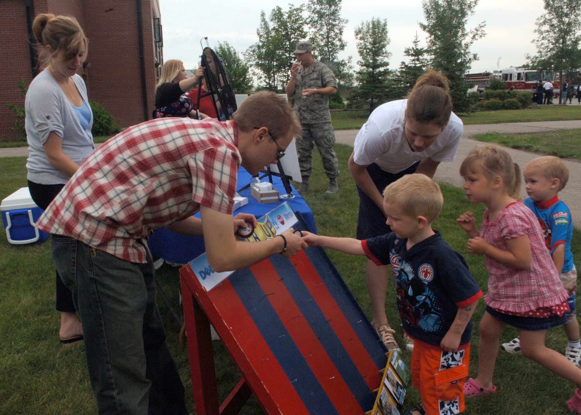 Clay Kraby, 319th Force Support Squadron, helps Eli Haslen, 4, play the Match Up game during a Wingman Day picnic July 22. The Wingman Day picnic included food, games and opportunities for members and their families to win miscellaneous prices. (U.S. Air Force photo/Senior Airman Tiffany Colburn) 
