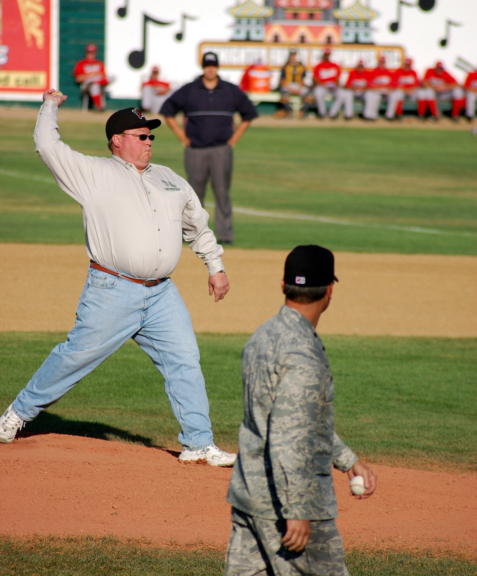 Steve Grooms, 1st Liberty Federal Credit Union president and CEO, throws a first pitch during Military Appreciation night at Centene Stadium July 18. 1st Liberty sponsored the event by purchasing admission tickets for all military ID card holders.  Lt. Col. Robert Vercher, 12th Missile Squadron commander (foreground) was the the military first pitch thrower. (U.S. Air Force photo/Airman 1st Class Dillon White)