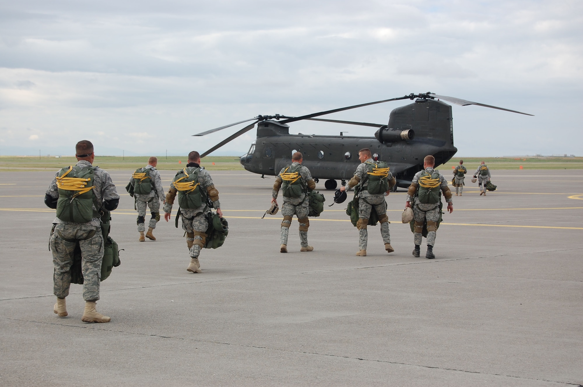 Roughly 11 members of the 819th RED HORSE Squadron airborne team walk toward the Montana Army National Guard Chinook helicopter before their quarterly jump training at Malmstrom Air Force Base July 23. The parachutes weigh about 40 pounds each and their backpacks and gear weigh between 60 to 75 pounds. (U.S. Air Force photo/Senior Airman Eydie Sakura)