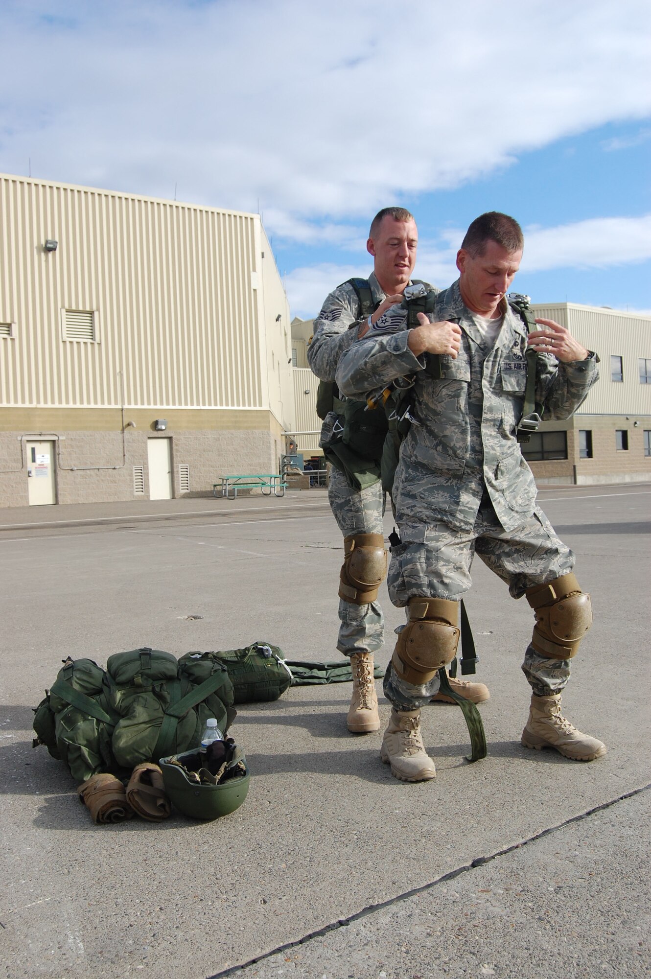 Tech. Sgt. Charles Hardy receives assistance from fellow 819th RED HORSE Squadron airborne team member, Staff Sgt. John Sinner, prior to a parachute jump out of a Chinook helicopter July 23. Roughly 11 members of the 819th RHS airborne team performed jump training at Malmstrom Air Force Base with aerial assistance from the Montana Army National Guard. The parachutes weigh about 40 pounds each and their backpacks and gear weigh between 60 to 75 pounds. (U.S. Air Force photo/Senior Airman Eydie Sakura)