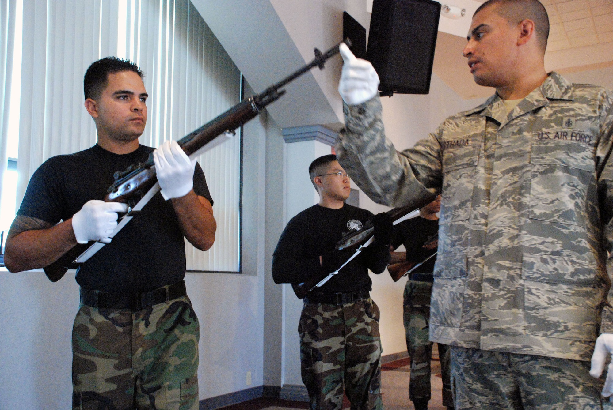 Senior Airman Kwinton Estacio, Malmstrom base honor guard member, listens to Tech. Sgt. Jason Estrada, NCO in charge of the base honor guard training program, as he shows the students how to perfect their movements and stay in rhythm with the sic other members of the firing party. (U.S. Air Force photo/Airman 1st Class Daryl Knee)