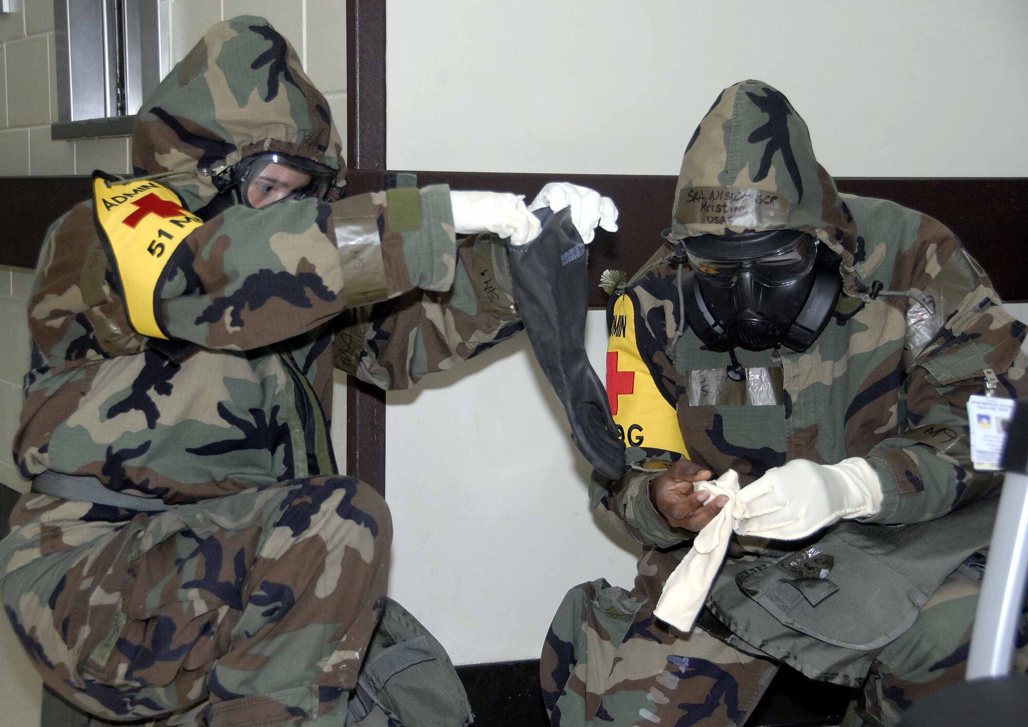 OSAN AIR BASE, Republic of Korea -- Senior Airman Gabriela Nario, (left), and Senior Airman Corey Gray, 51st Medical Group patient administrative technicians, don their chemical warfare gear during a base-wide exercise here July 22. The patient administrative technicians are responsible for inprocessing patients and ensuring patients are sent to the proper areas for treatment. (U.S. Air Force photo/Staff Sgt. Lakisha Croley)
