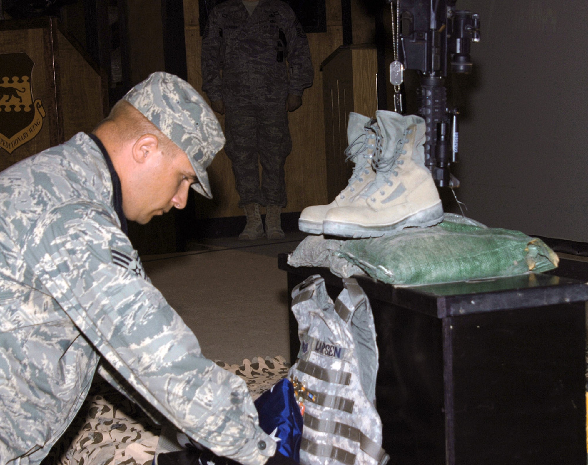 Staff Sgt. Jerred Mitchell presents a ceremonial flag at a memorial service for Tech. Sgt. Jackie Larsen in the Joint Base Balad Town Hall July 20 in Iraq.  Sergeant Larson, who died from non-combat related causes July 17, was a paralegal working with the Law and Order Task Force of the 732nd Expeditionary Support Squadron. Her duties placed her at Forward Operating Base Shield where she served as the NCO in charge of all personnel movements for the LAOTF. She was deployed from Beale Air Force Base, Calif. and her hometown was Tacoma, Wash. Sergeant Mitchell is a Joint Base Balad Honor Guard member. (U.S. Air Force photo/Tech. Sgt. Richard Lisum)