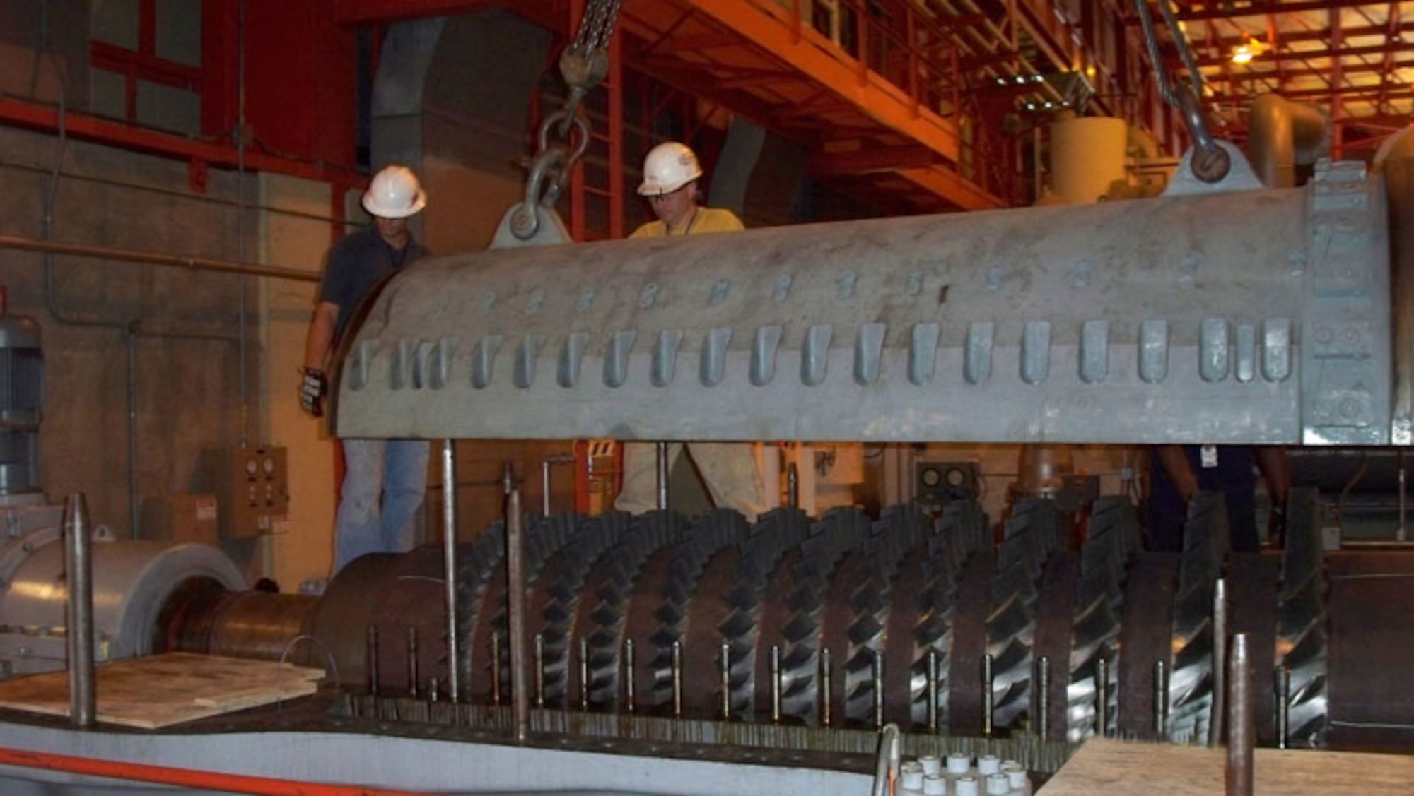 From right to left, Nathan Crocker, Aerospace Testing Alliance Machinist, and Kevin Glasser, Jacobs Industrial Services, Inc. ironworker-rigger, supervise the lowering of the stator cap over the A21 high stage compressor rotor Aeropropulsion Systems Test Facility (ASTF) during a major maintenance and repair outage that included significant repairs to ASTF's RC1 Cooler.  (Photo by Warner Holt) 