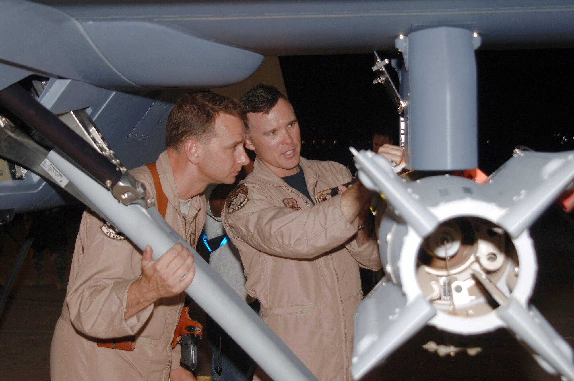 Maj. John Chesser (left) Lt. Col. Micah Morgan inspect the arming devices on a munition affixed to an MQ-9 Reaper July 17 at Joint Base Balad, Iraq. The Reaper can carry up to 3,750 pounds of munitions, including GBU-12 laser-guided bombs and Hellfire missiles. Colonel Morgan is the 46th Expeditionary Reconnaissance and Attack Squadron commander, and Major Chesser is a Reaper pilot with the 46th ERAS. Both officers are deployed from Creech Air Force Base, Nev. (U.S. Air Force photo/Tech. Sgt. Richard Lisum) 
