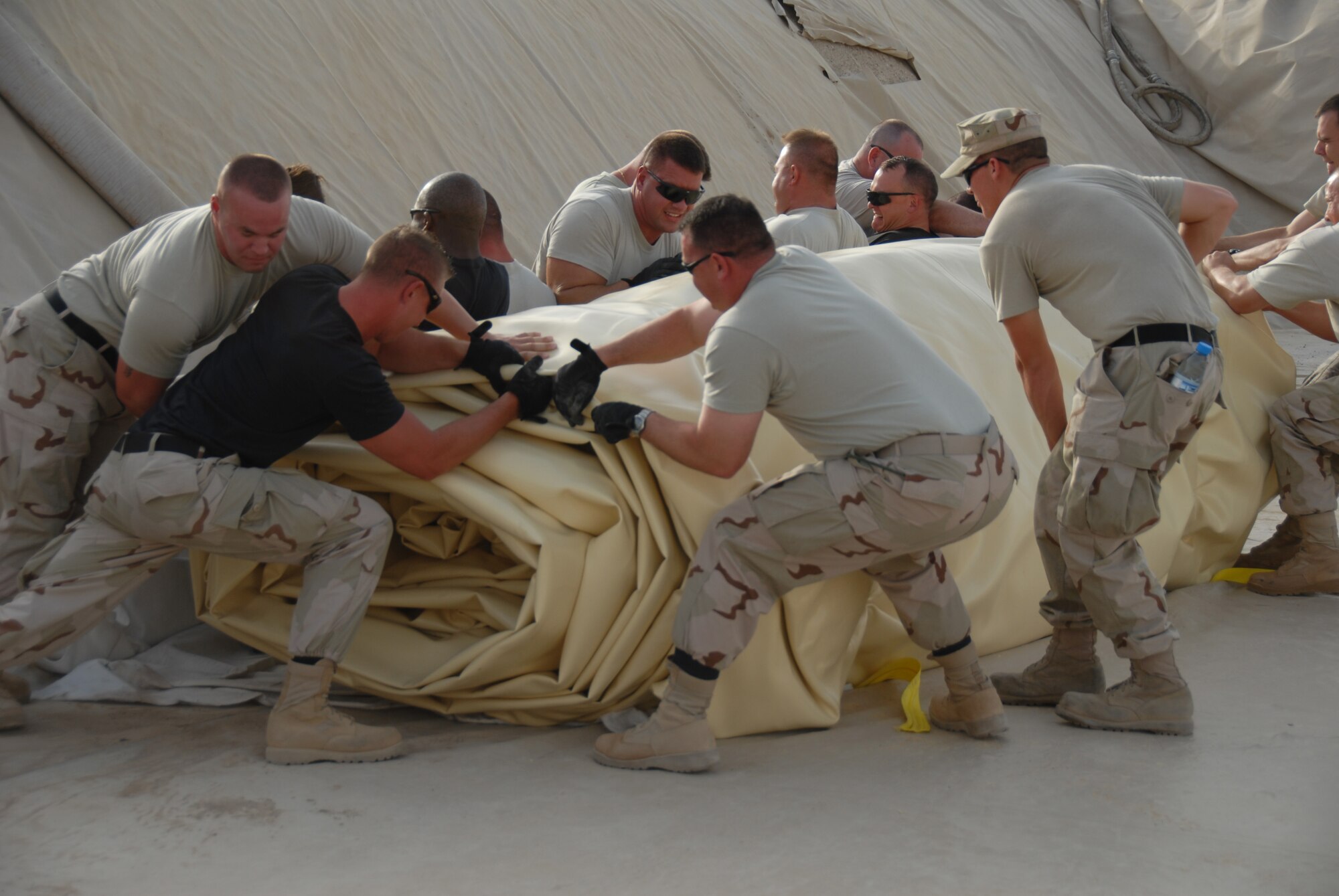 Members of the 380 Expeditionary Logistics Readiness Squadron, work as a team to roll out a new fuel bladder July 24. The fuel bladder weighs approximately 2.5 tons empty and it can hold 200,000 gallons of fuel. ELRS changed out the bladder due to normal wear and tear and climate conditions.(U.S. Air Force photo/Tech. Sgt. Christopher A Campbell)