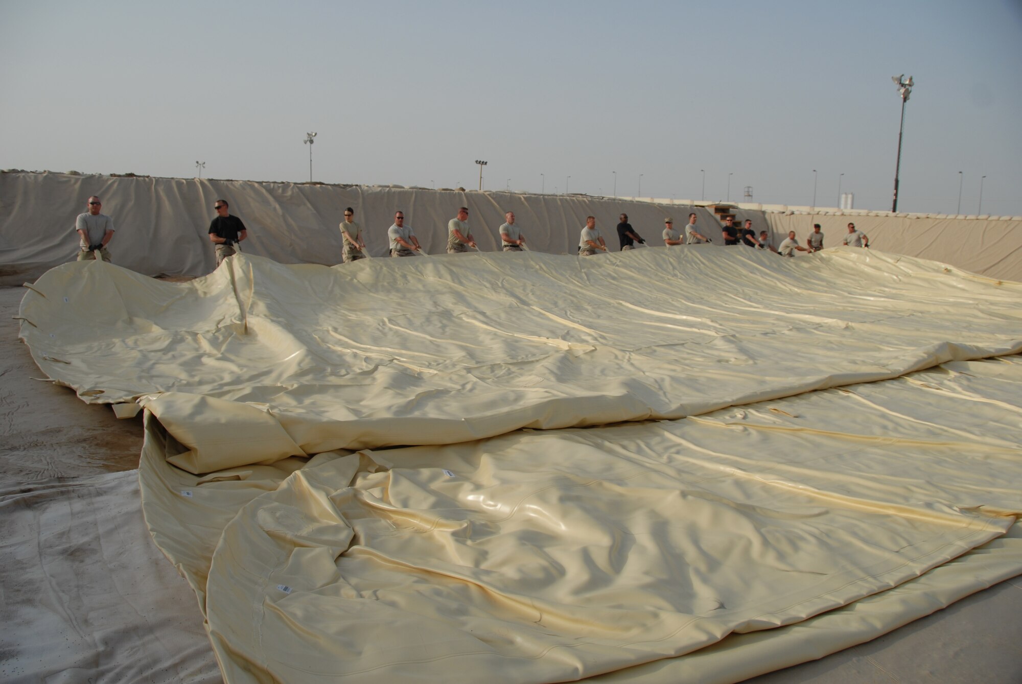 Members of the 380 Expeditionary Logistics Readiness Squadron, work as a team to spread out a new fuel bladder July 24. The fuel bladder weighs approximately 2.5 tons empty and it can hold 200,000 gallons of fuel. ELRS changed out the bladder due to normal wear and tear and climate conditions.(U.S. Air Force photo/Tech. Sgt. Christopher A Campbell)