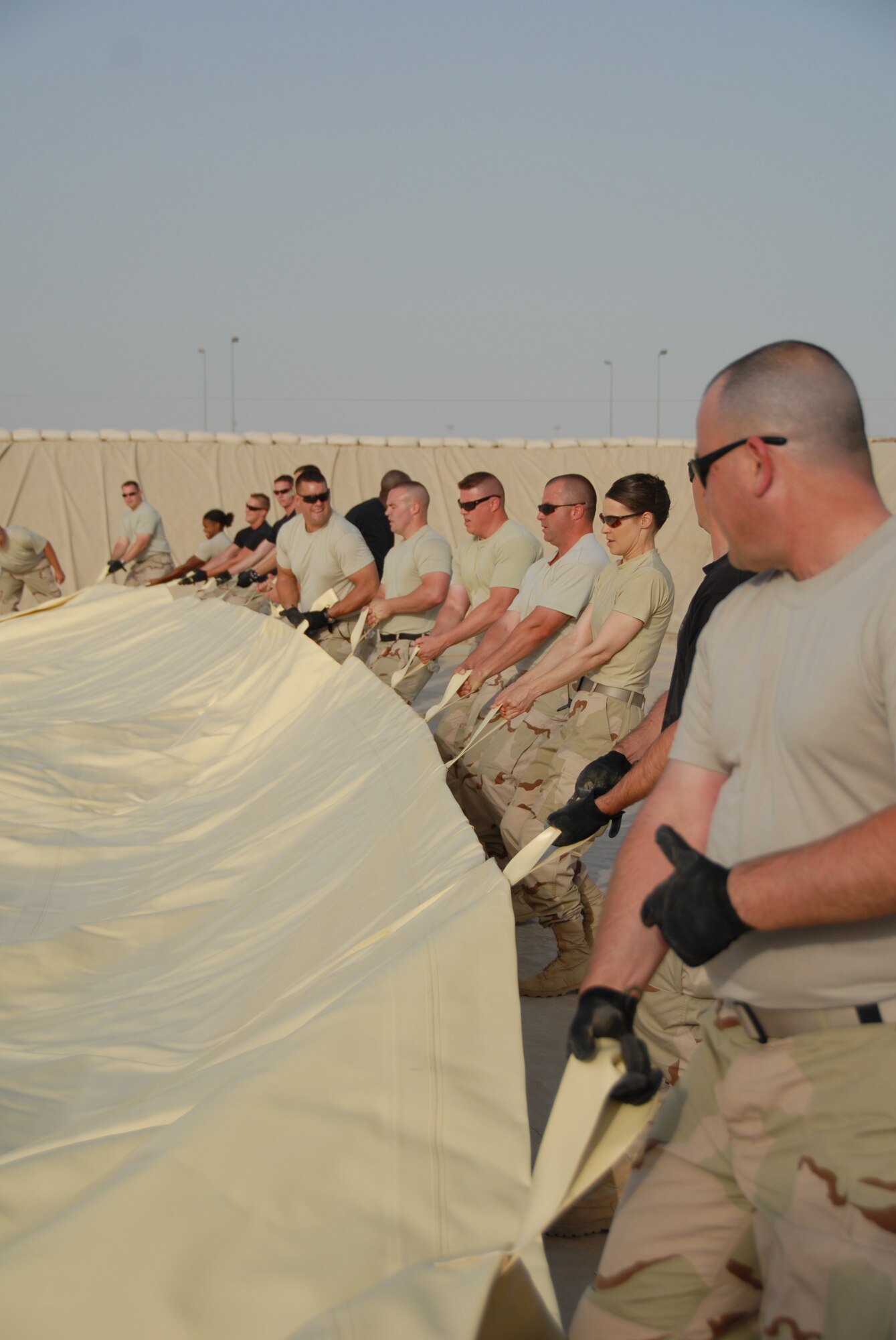 Members of the 380 Expeditionary Logistics Readiness Squadron, work as a team to spread out a new fuel bladder July 24. The fuel bladder weighs approximately 2.5 tons empty and it can hold 200,000 gallons of fuel. ELRS changed out the bladder due to normal wear and tear and climate conditions.(U.S. Air Force photo/Tech. Sgt. Christopher A Campbell)