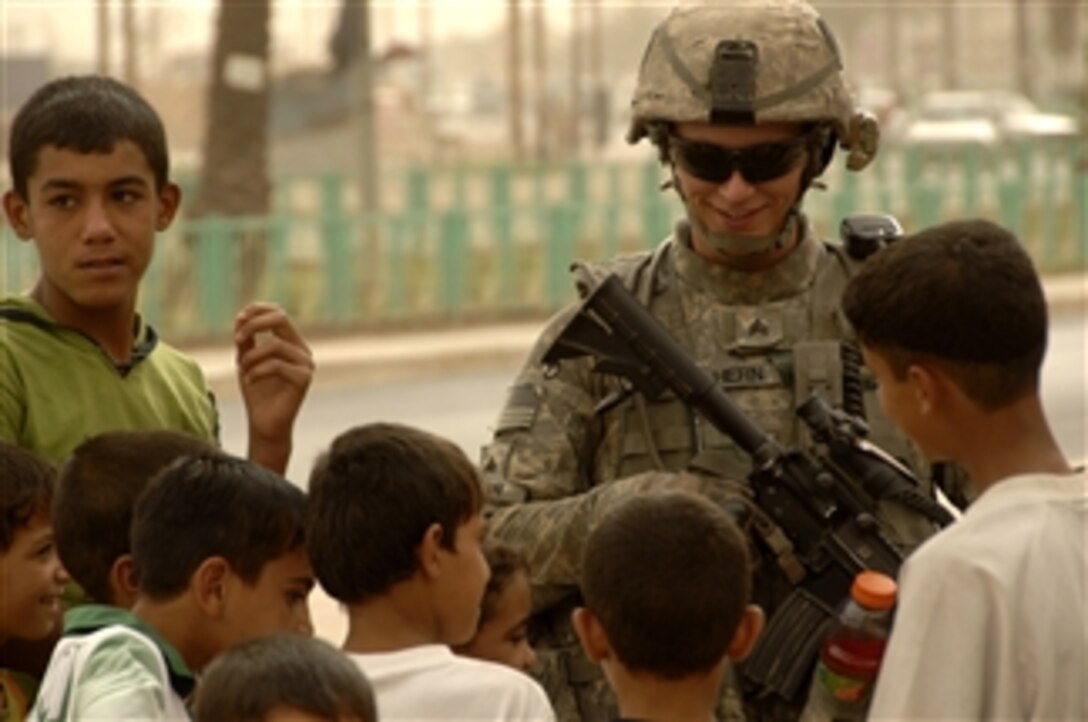 A U.S. Army soldier talks with Iraqi children during a patrol in the Shula district of Baghdad, Iraq, on July, 20, 2008.  The soldiers are with Bravo Troop, 1st Squadron, 75th Cavalry Regiment, 2nd Brigade Combat Team, 101st Airborne Division.  