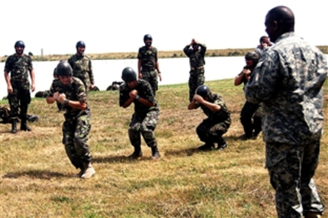 U.S. Army Sgt. 1st Class Elijah Acklin, right, guides Romanian army paratroopers through airborne pre-jump training on Mihail Kogalniceanu Air Base, Romania, July 15, 2008. Acklin is assigned to the 5th Quartermaster Company.