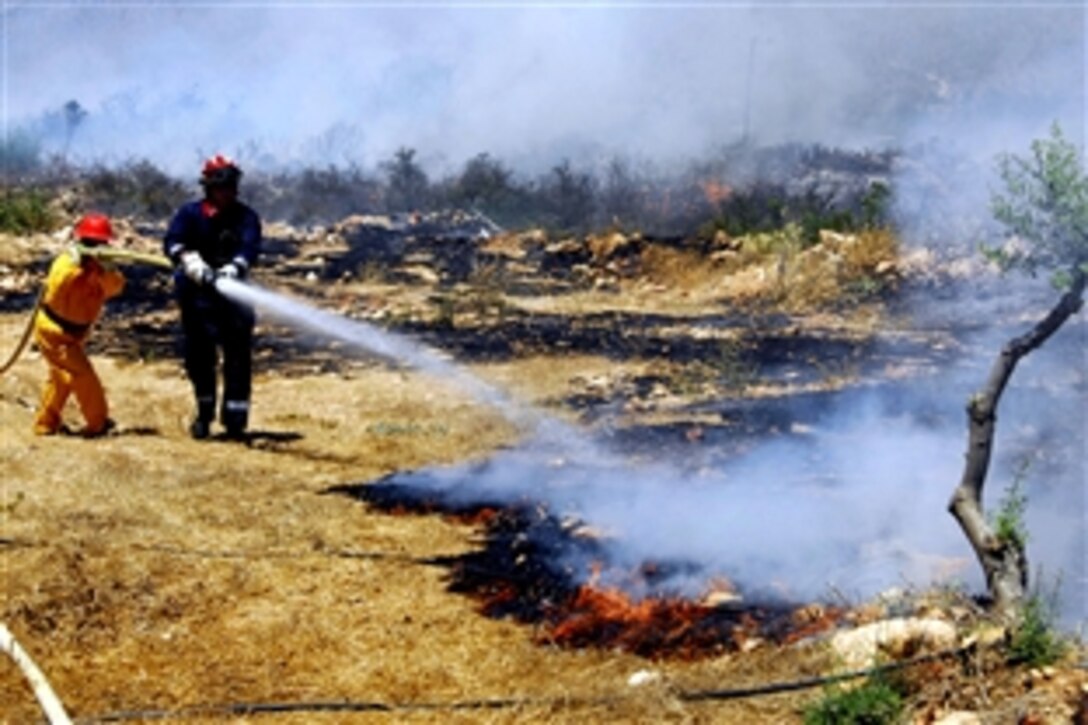 U.S. Navy Civlian Firefighters Georgios Sgouromalis, left, and Robert Womble fight a brush fire near the Chania International Airport in Crete, Greece, July 23, 2008. Naval Support Activity Souday Bay responded to a request for assistance from local authorities and dispatched 21 firefighters and five emergency vehicles to the scene along with two Seabees and other personnel for ground support and liaison.