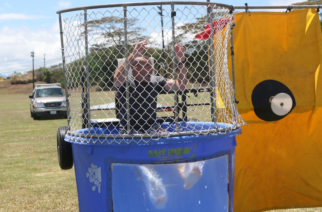 Lt. Col.  John Sharkey, HQ&SVC BN's executive officer, shows his 'esprit de corps' as he gets dropped into the dunk tank by Marines and their famalies during the Headquarters and Service Battalion family day July 25 here.