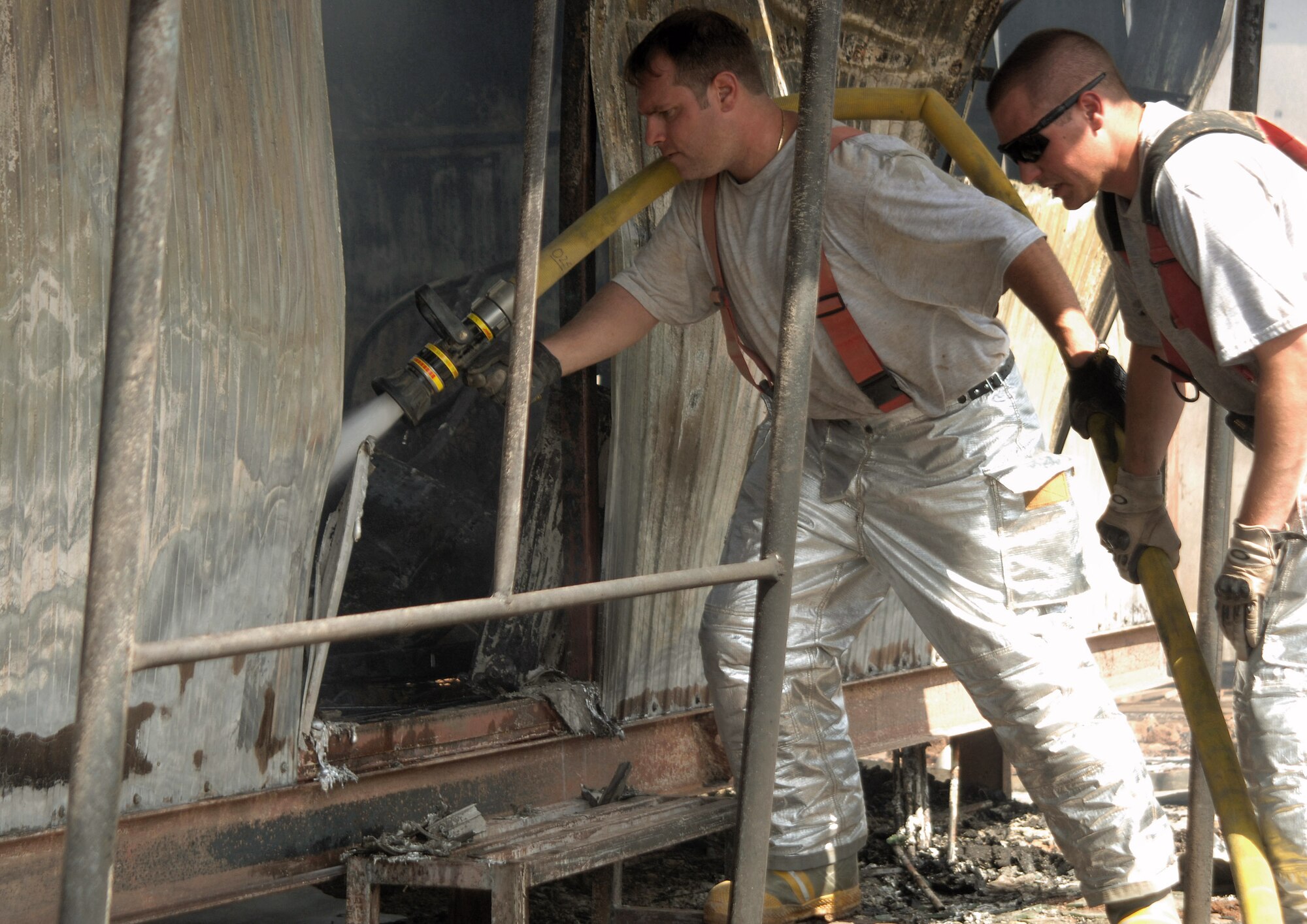 Firefighters Staff Sgts. Chris Bakupoulos (left) and Van Smith douse the remainder of a fire that destroyed a collection of trailers July 22 at Joint Base Balad, Iraq. The Airmen helped contain a two-alarm fire, limiting the damage to six closely situated buildings. Firefighters terminated the emergency at approximately 4:30 p.m., and crews remained on scene to extinguish hotspots and prevent a new fire from starting. Both Airmen are deployed from Charleston Air Force Base, S.C. (U.S. Air Force photo/Senior Airman Thomas Trower) 
