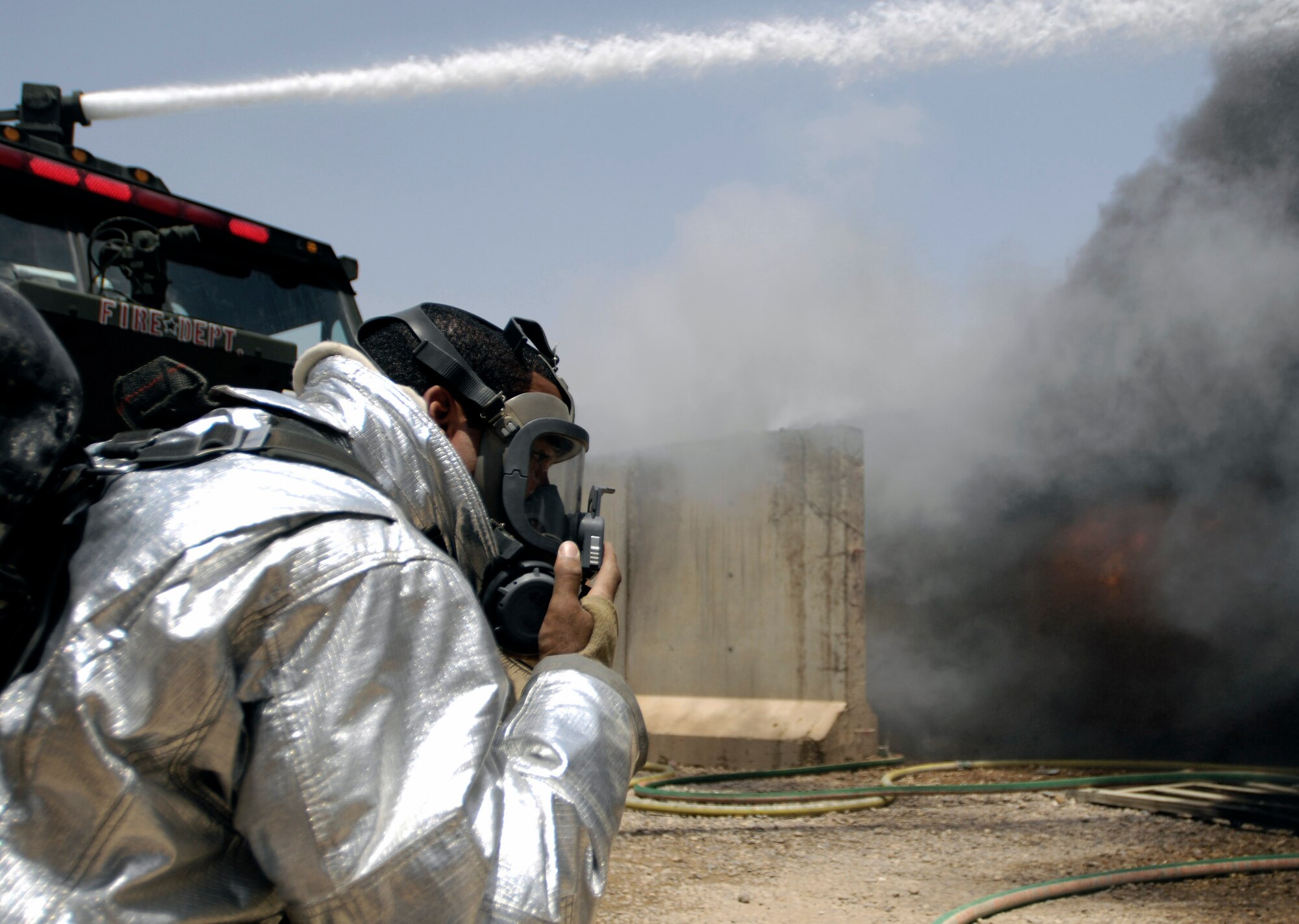 Airman 1st Class Zachary Auxilly dons protective gear as he prepares to fight a blaze July 22 at Joint Base Balad, Iraq. Air Force and Army firefighters teamed up to contain the two-alarm fire, limiting the damage to six closely situated buildings. No one was injured in the fire, although three firefighters were treated for heat stress-related conditions and released. Airman Auxilly is deployed from Misawa Air Base, Japan. (U.S. Air Force photo/Airman 1st Class Jason Epley) 