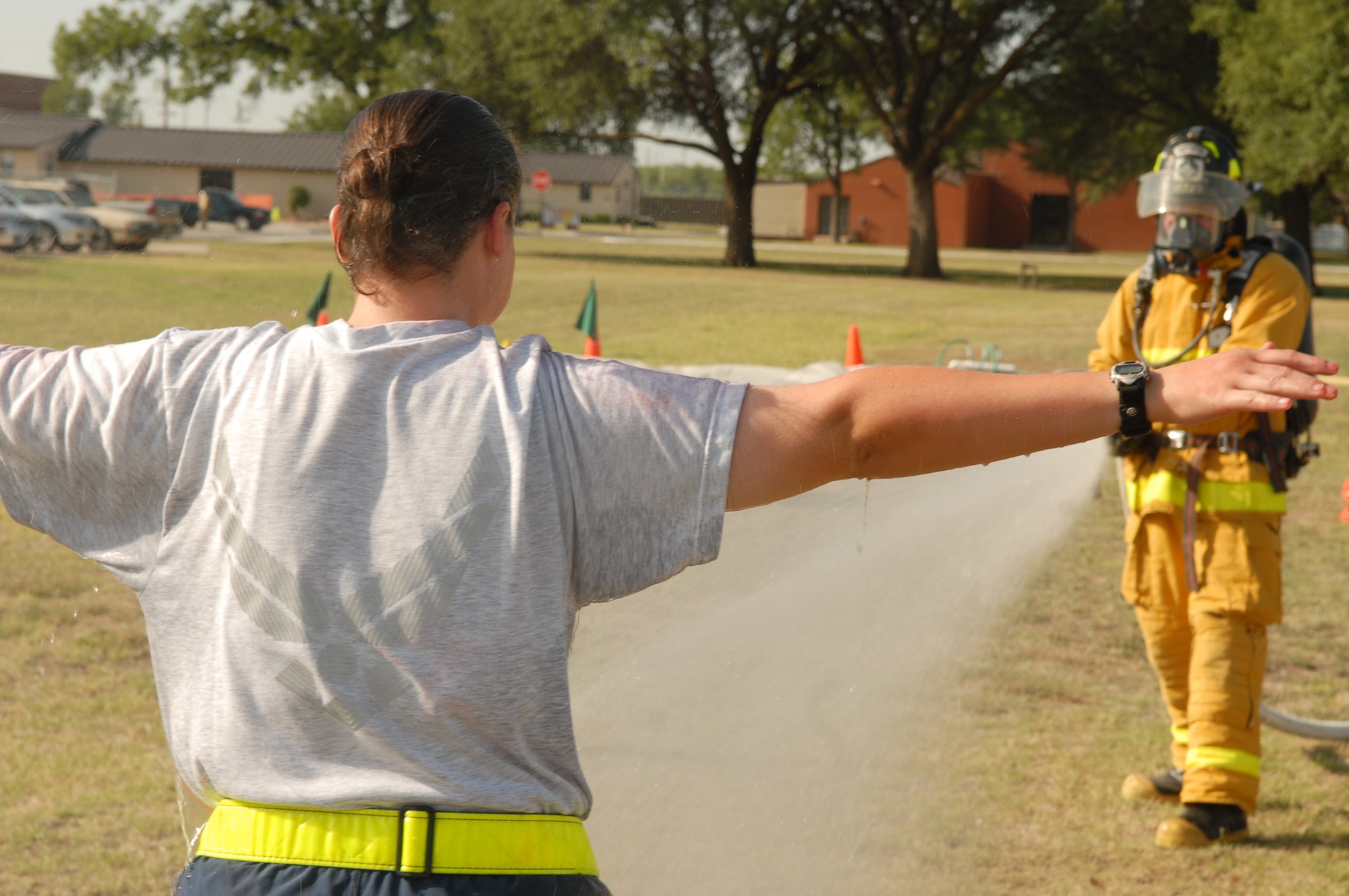 A member of the Goodfellow Air Force Base Fire Department (right) sprays down an exercise participant after a simulated chemical attack during the basewide exercise July 18.  (U.S. Air Force photo by Staff Sgt. John Barton)
