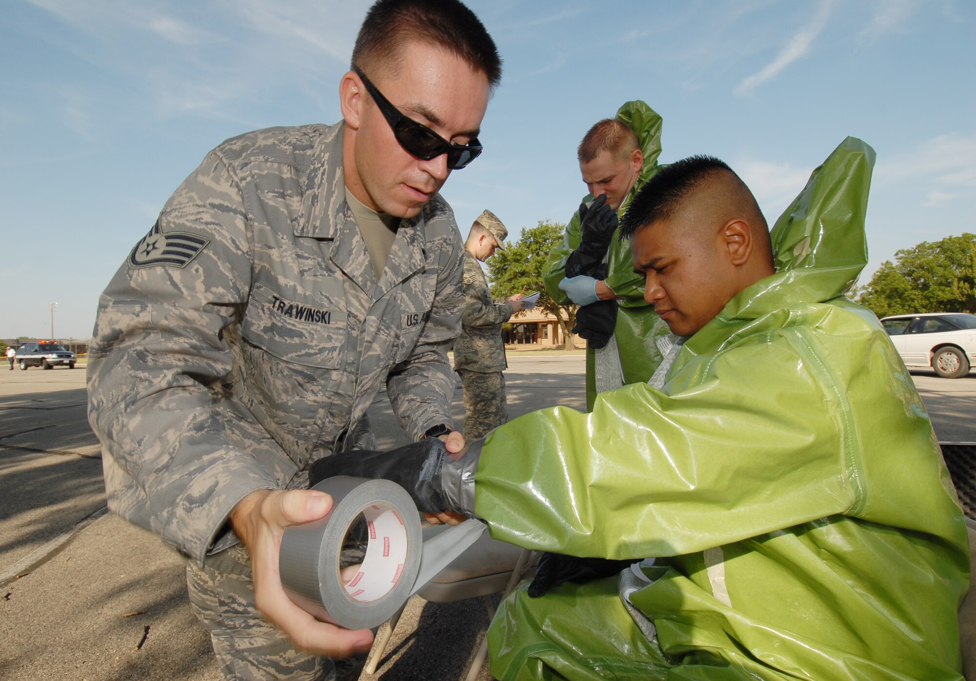 Staff Sgt. Marcin Trawinski helps Airman 1st Class Paolo Melendez suit up to enter a simulated chemical environment during Exercise Scarlet Hawk 08-06 July 18 at the base theater. Both Sergeant Trawinski and Airman Melendez are members of the 17th Medical Group’s Bioenvironmental Engineering office. (U.S. Air Force photo by Staff Sgt. John Barton)