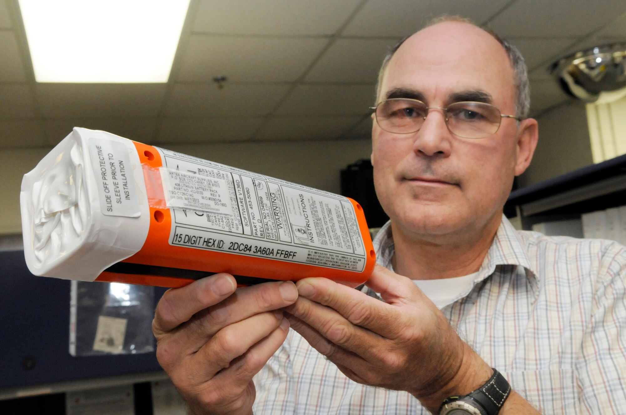 Barry Fulton, 565th ACSS program manager, holds the lithium battery pack for an Emergency Locator Transmitter for the C-5. The ELT is equipped with an identification number to aid in rescue efforts in times of distress. U. S. Air Force photo by Sue Sapp