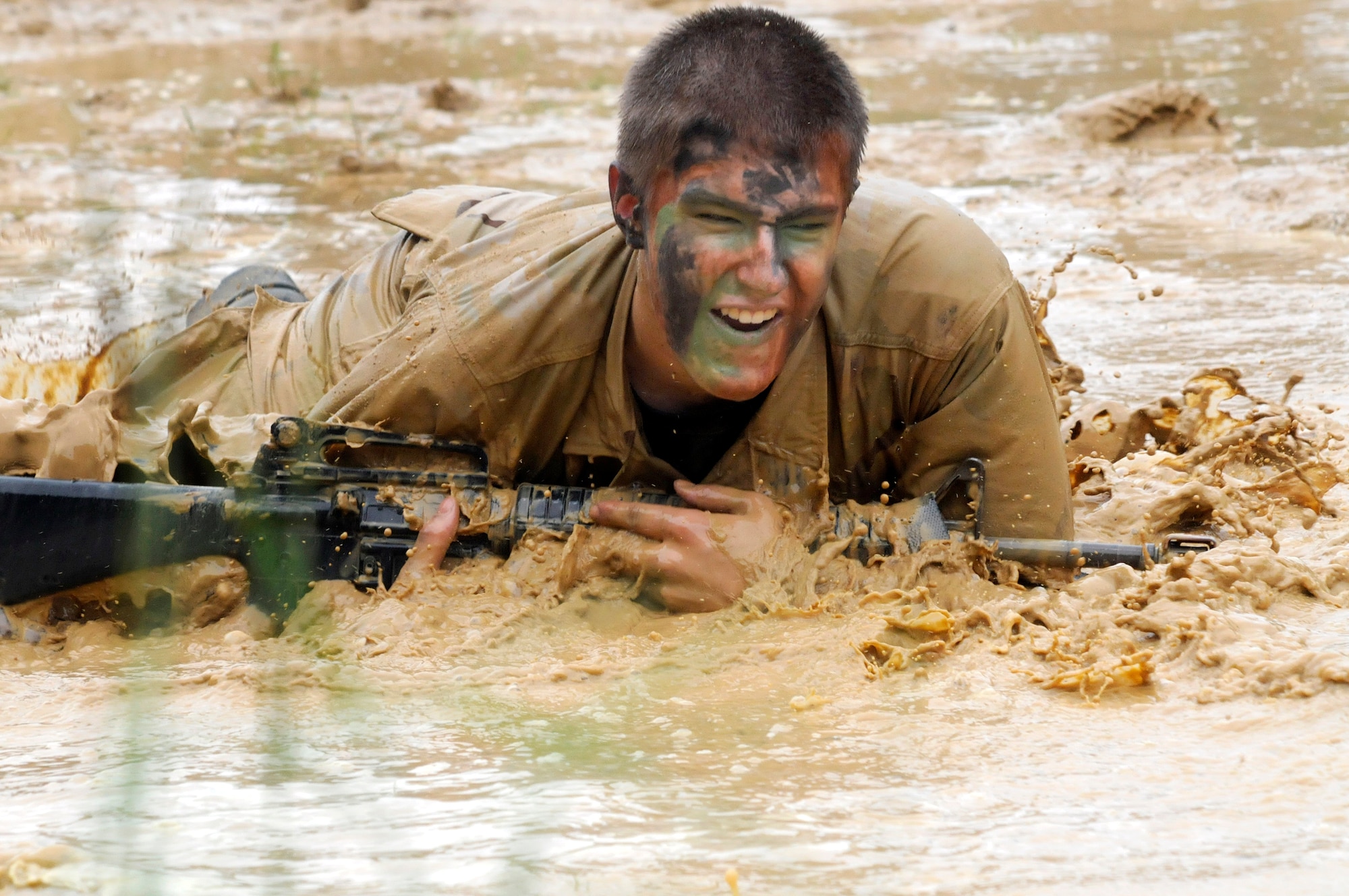 Cadet Steve Gregory does a high crawl with weapon through the mud pit during Gator Gully training July 23.  U. S. Air Force photo by Sue Sapp