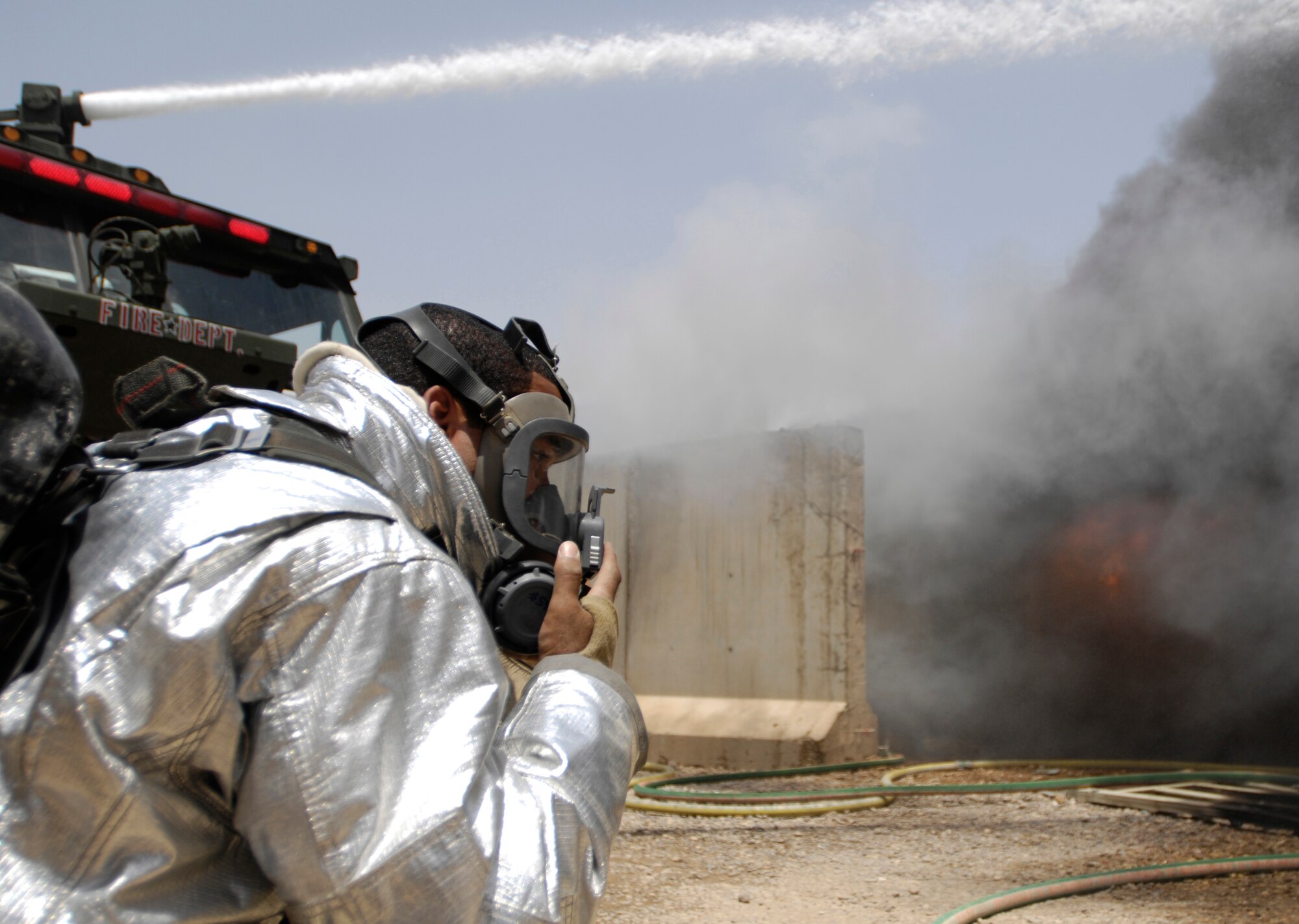 JOINT BASE BALAD, Iraq -- Airman 1st Class Zachary Auxilly dons protective gear as he prepares to fight a blaze here July 22. Air Force and Army firefighters teamed up to contain the two-alarm fire, limiting the damage to six closely situated buildings. No one was injured in the fire, although three firefighters were treated for heat stress-related conditions and released. Airman Auxilly is deployed from Misawa Air Base, Japan. (U.S. Air Force photo/Airman 1st Class Jason Epley)