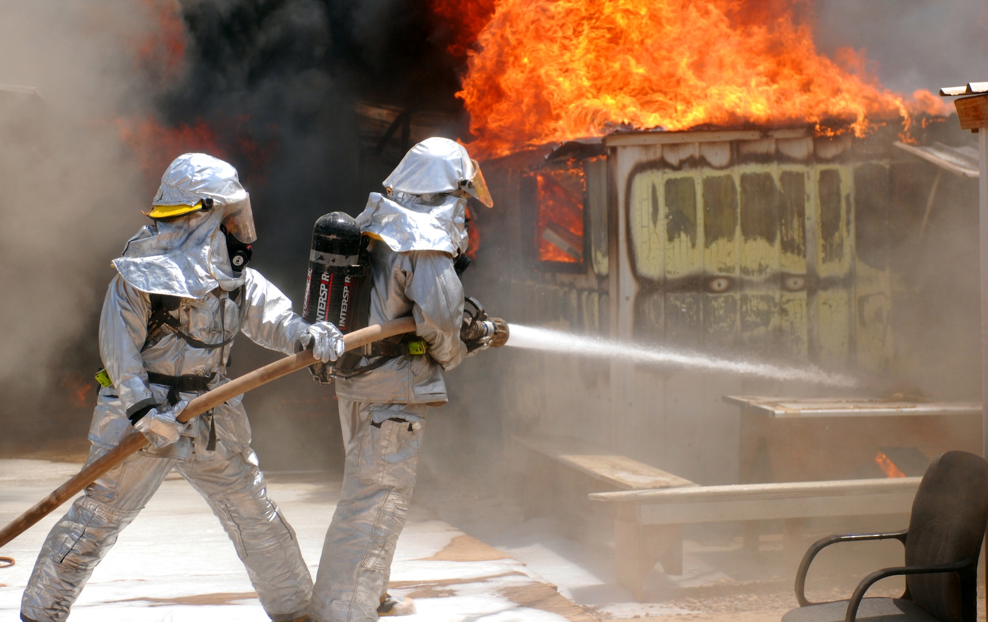 JOINT BASE BALAD, Iraq -- Firefighters battle to control a blaze here that destroyed six metal framed buildings used as workspace, storage and living quarters July 22. No injuries were reported from the fire, but a high temperature of 117 degrees forced three firemen to be treated at the Air Force Theater Hospital for heat stress-related injuries, they were later released. The cause of the fire is under investigation. (U.S. Army photo/Sgt. Gary Hawkins)