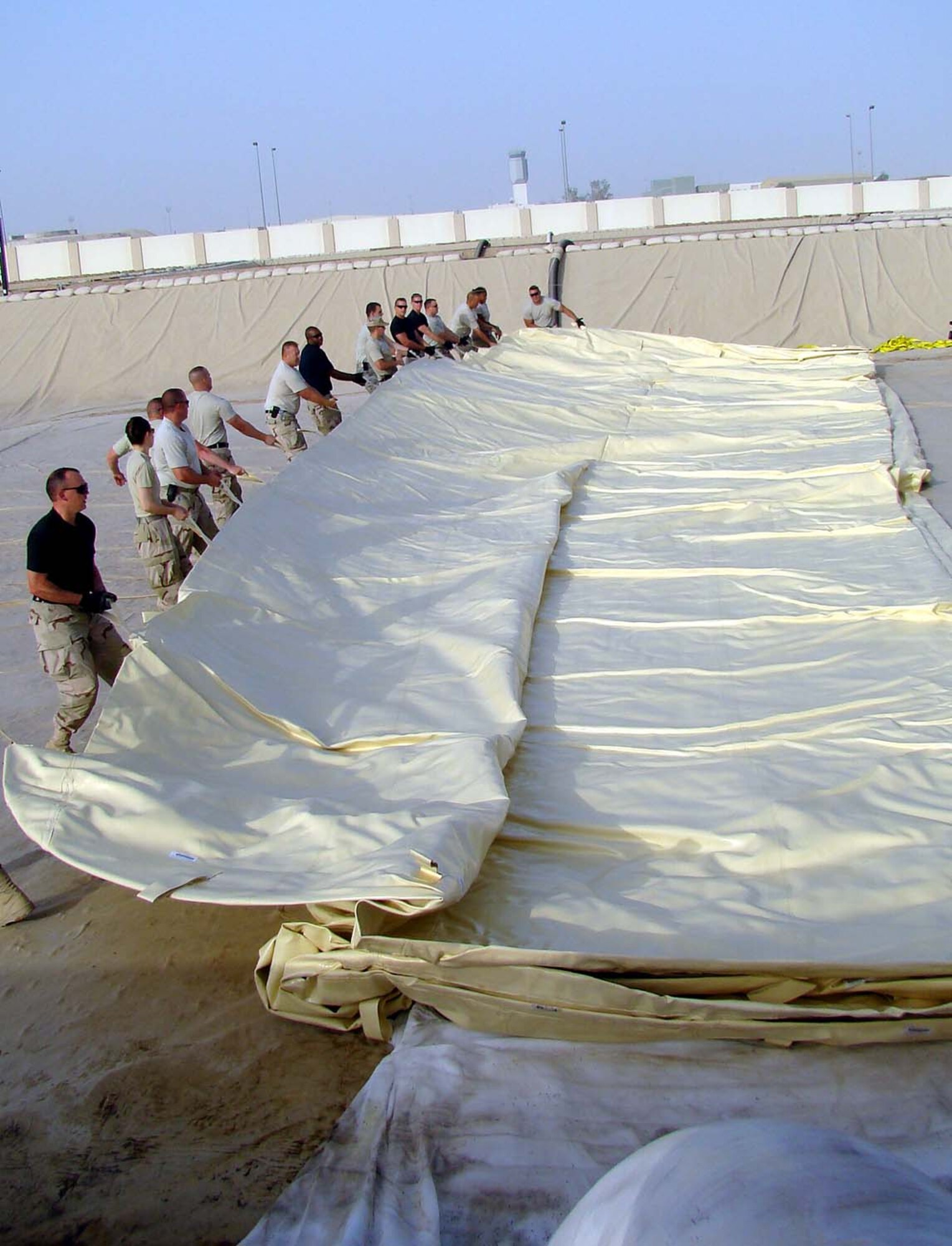 Volunteers joined the 380th Expeditionary Logistics Readiness Squadron to roll out a new fuel bladder Thursday. The fuel bladder weighs approximately 2.5 tons empty and it can hold 200,000 gallons of fuel. ELRS changed out the bladder Thursday due to normal wear and tear and climate conditions. (U.S. Air Force photo/Tech. Sgt. Denise Johnson)
                            