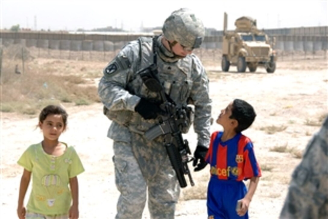 U.S. Army Sgt. Luke Hathaway walks with Iraqi children as his unit gets ready to conduct a routine patrol around Forward Operating Base Loyalty in Eastern Baghdad, Iraq, July 21, 2008. Hathaway is assigned to the 10th Mountain Division's Headquarters Company, Special Troops Battalion, 4th Brigade Combat Team.
