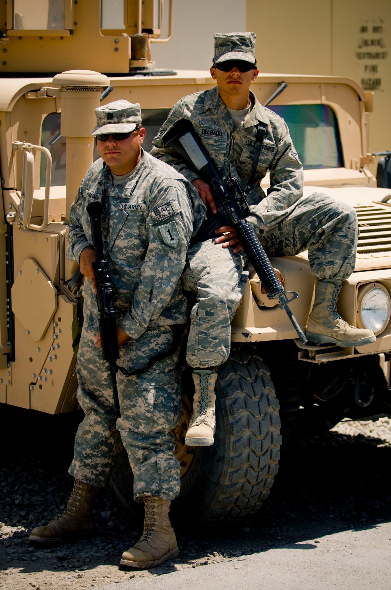 BAGRAM AIR FIELD, Afghanistan -- Army Private 1st Class Jerin Delgado (left) and his brother Senior Airman Matt Delgado (right) pose for a photo in front of a humvee here on July 17, 2008. The Delgado brothers found each other thousands of miles from home here at Bagram Air Field. The brothers are both stationed in and call Texas their home. (U.S. Air Force photo by Staff Sgt. Samuel Morse)