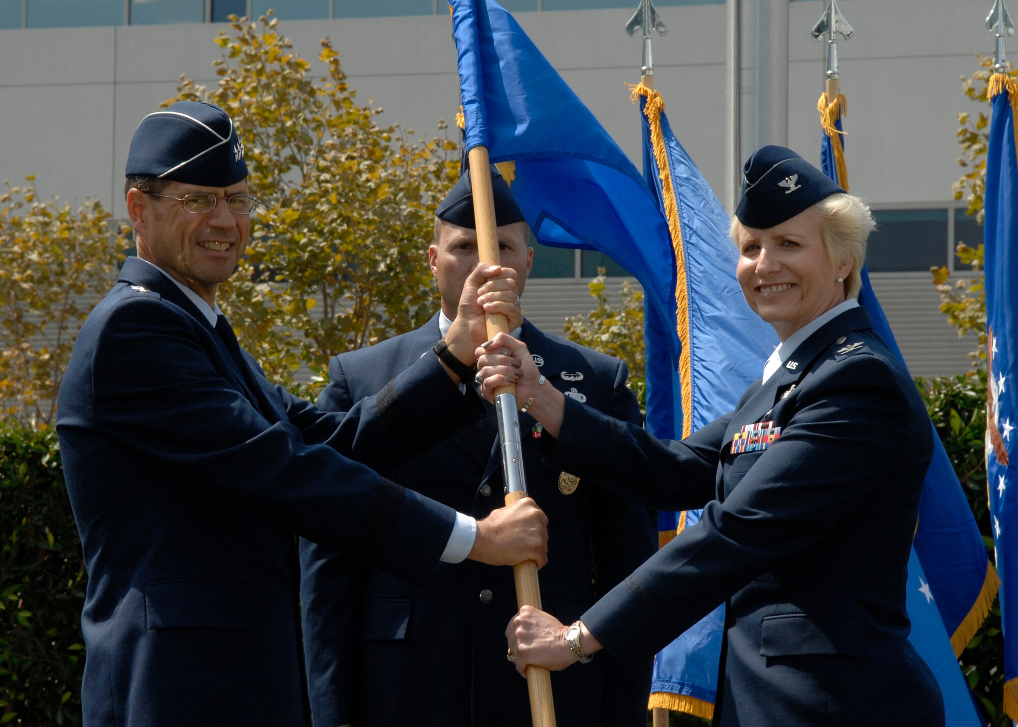 Col. Joseph Schwarz (left), 61st Air Base Wing commander, passes over his command to Col. Anita Latin (right) during the change of command ceremony which took place in the Shriever Space Complex courtyard at Los Angeles Air Force Base, July 22. (Photo by Stephen Schester)