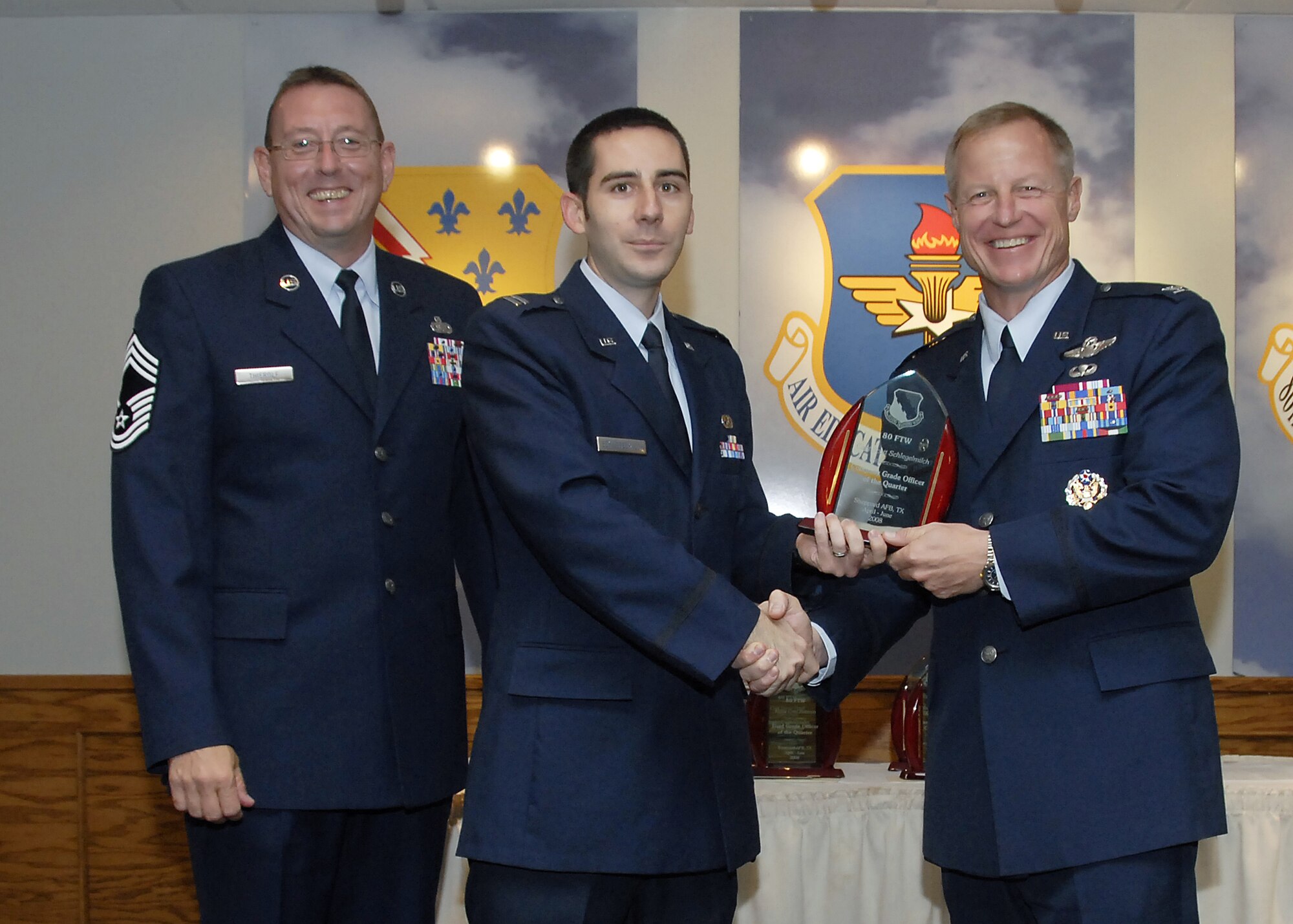Capt. Scott Schlegelmilch, center, accepts the Company Grade Officer of the Quarter award from 80th Flying Training Wing Commander David Petersen July 22 at the wing's quarterly awards banquet. Also pictured is wing Superintendent Chief Master Sgt. Norman Thierolf. (U.S. Air Force photo/Mike Litteken)