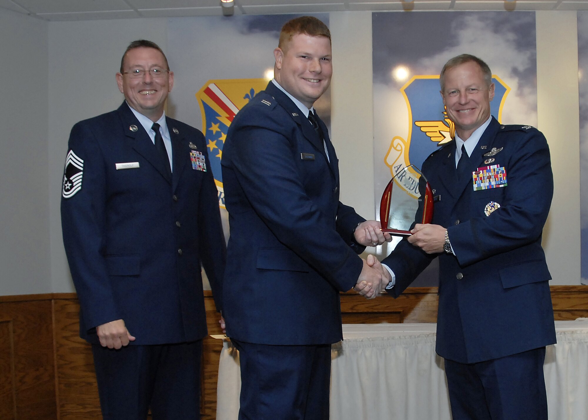 Capt. Andrew Stockman, center, accepts the Instructor Pilot of the Quarter award from 80th Flying Training Wing Commander David Petersen July 22 at the wing's quarterly awards banquet. Also pictured is wing Superintendent Chief Master Sgt. Norman Thierolf. (U.S. Air Force photo/Mike Litteken)